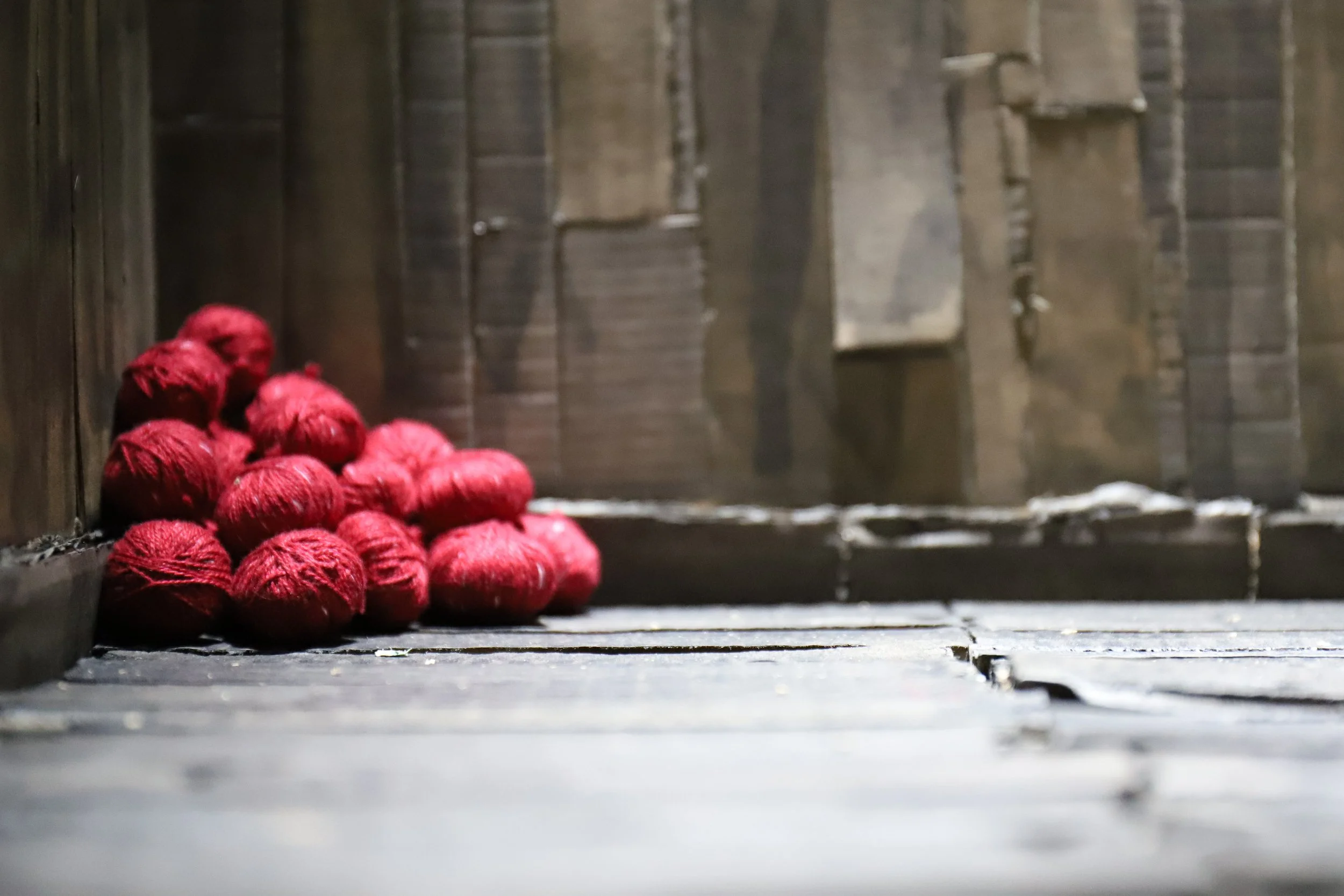 Palline di filo rosso accatastate in un angolo di una stanza di legno.