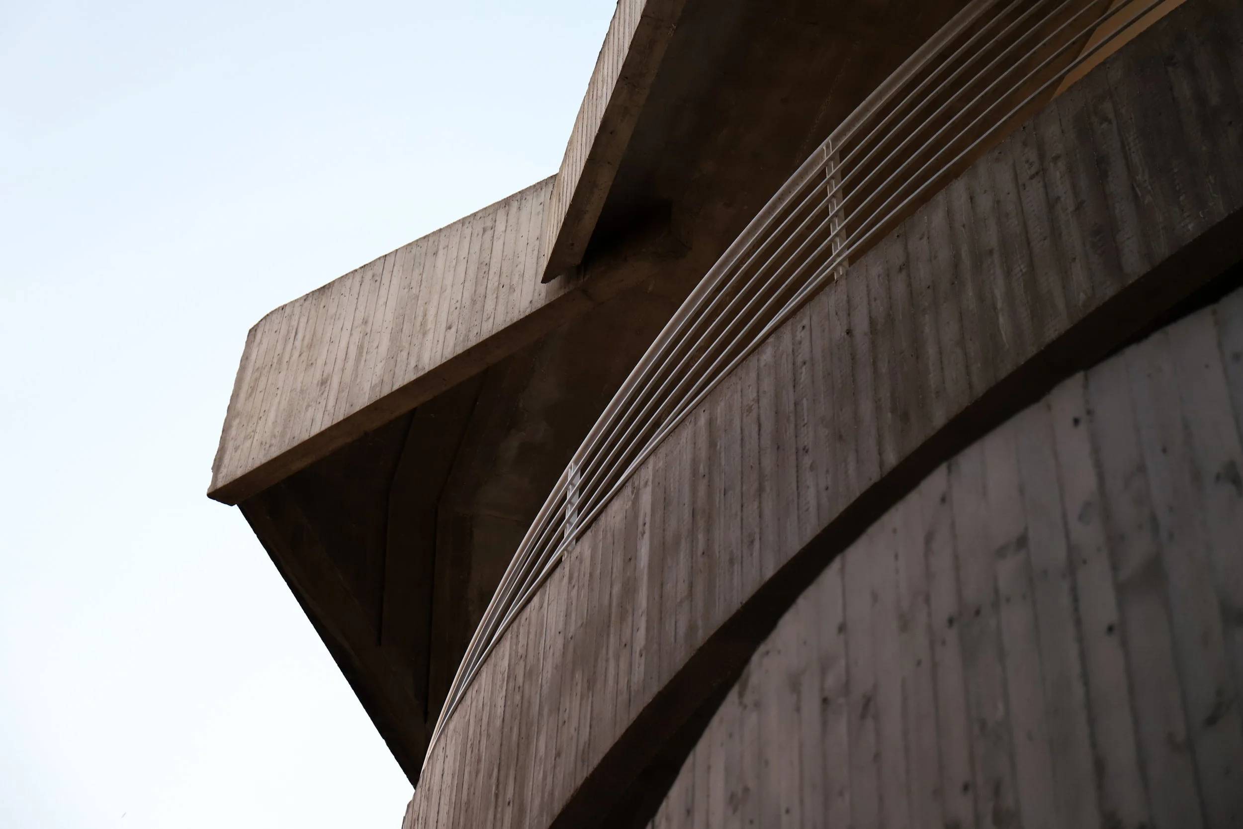Vista di un edificio in cemento con un parapetto in metallo, vista dall'angolatura sottostante.