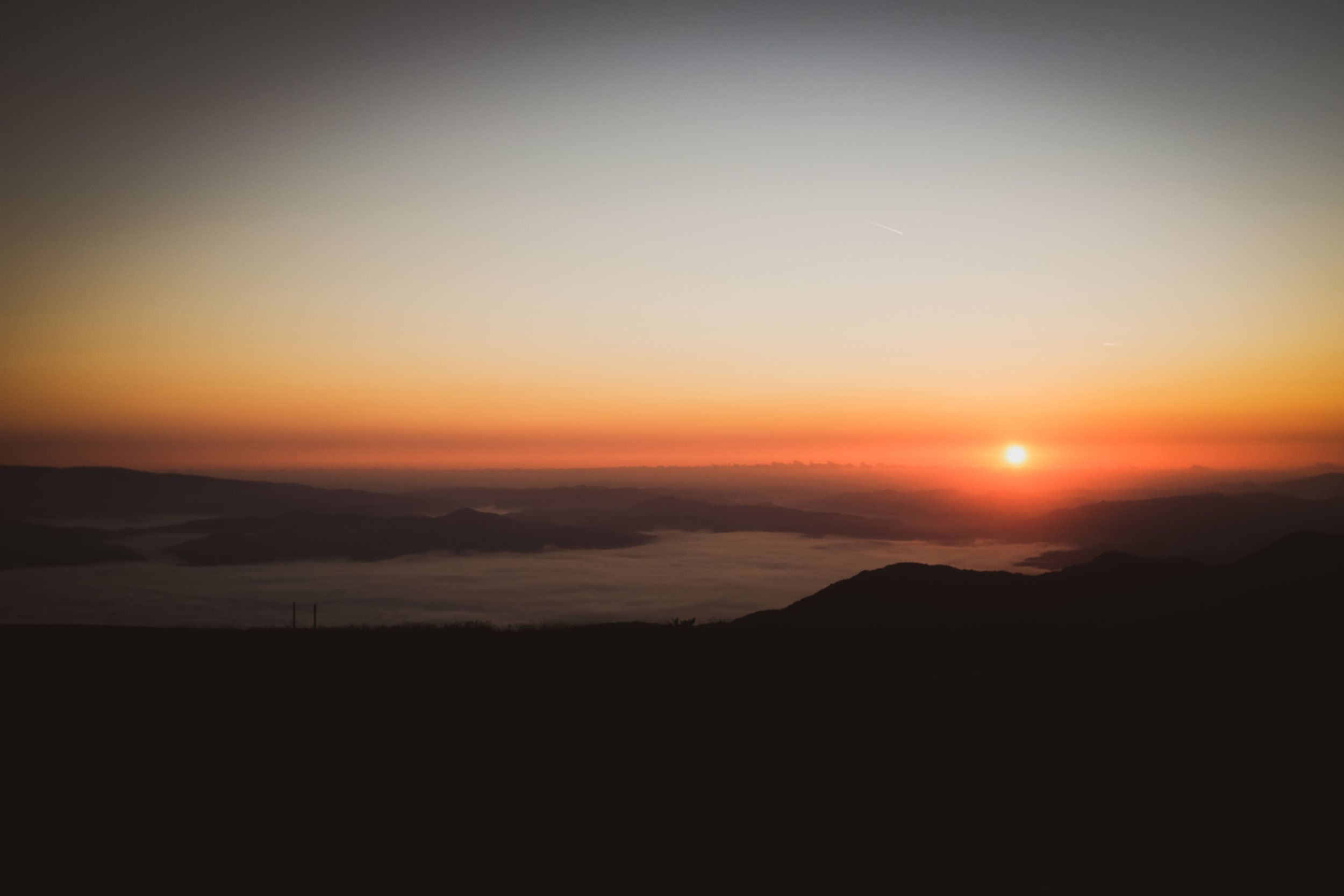 Tramonto sopra una catena montuosa con foschia e cielo colorato