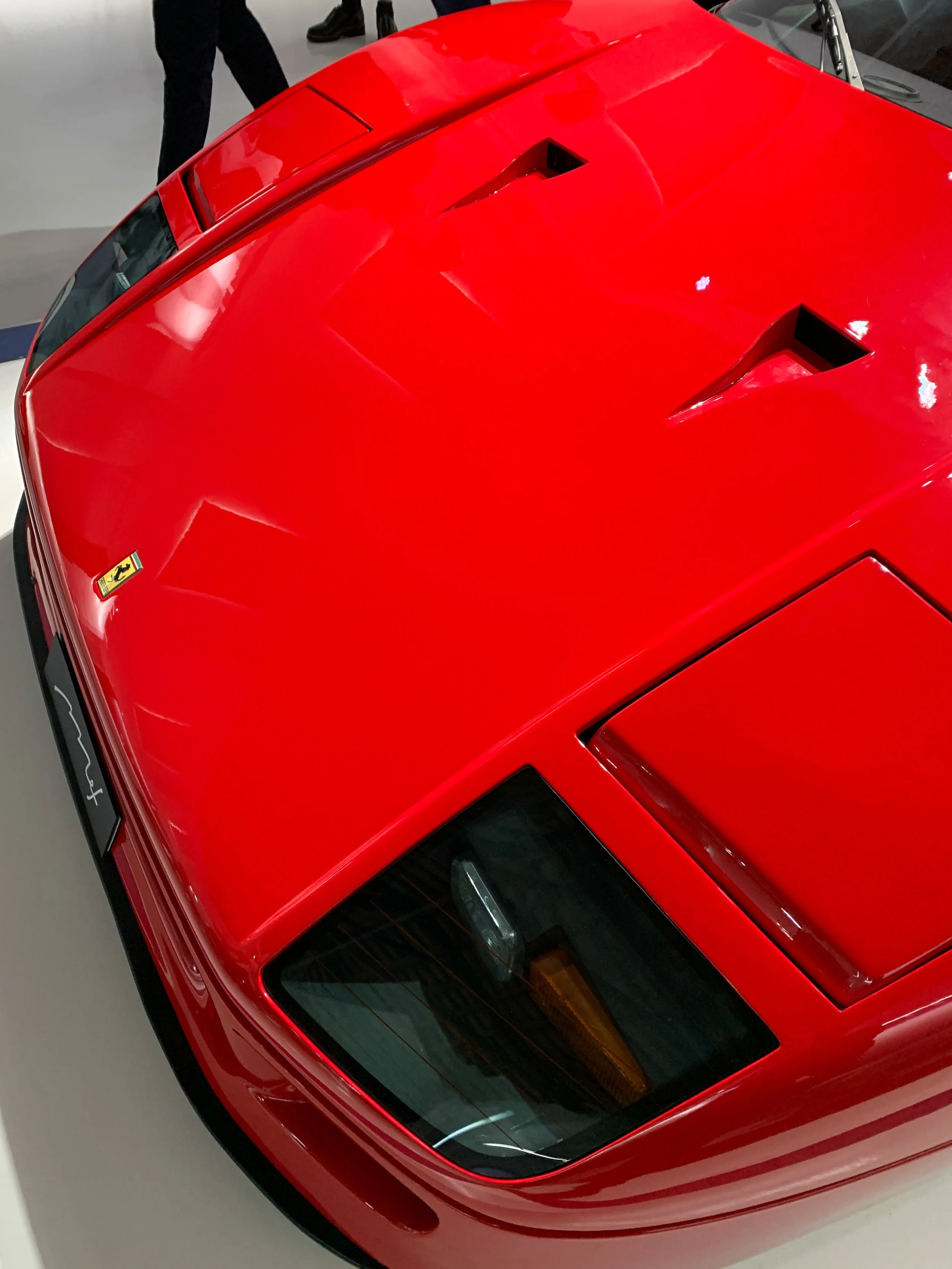 Particolare del cofano di un'auto da corsa rossa Ferrari, con prese d'aria e dettagli aerodinamici.