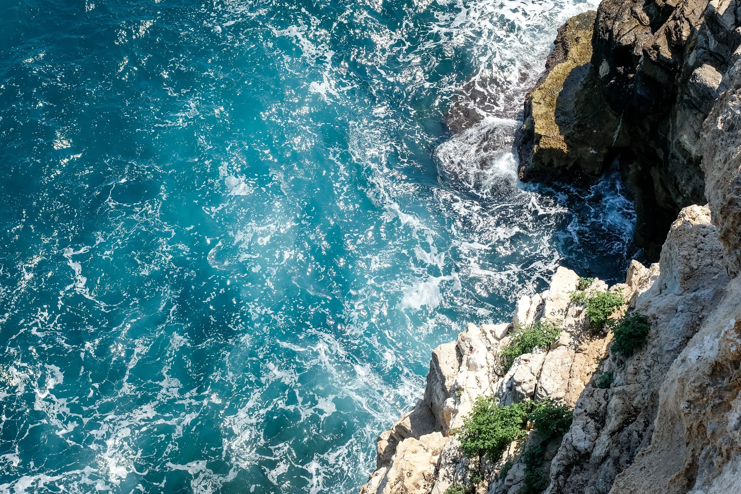 Vista delle onde azzurre che si infrangono contro le rocce sulla costa.