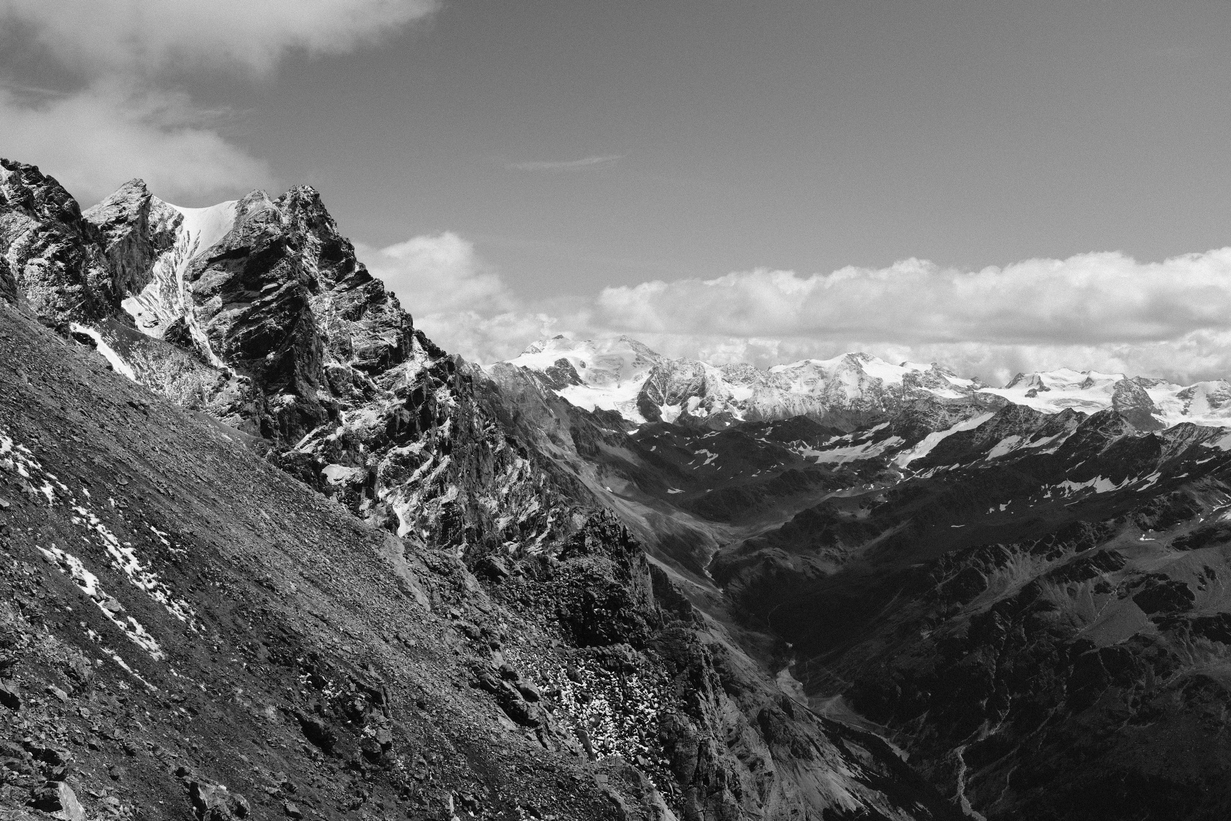 Paesaggio montano con piccole cime e valli, in bianco e nero.