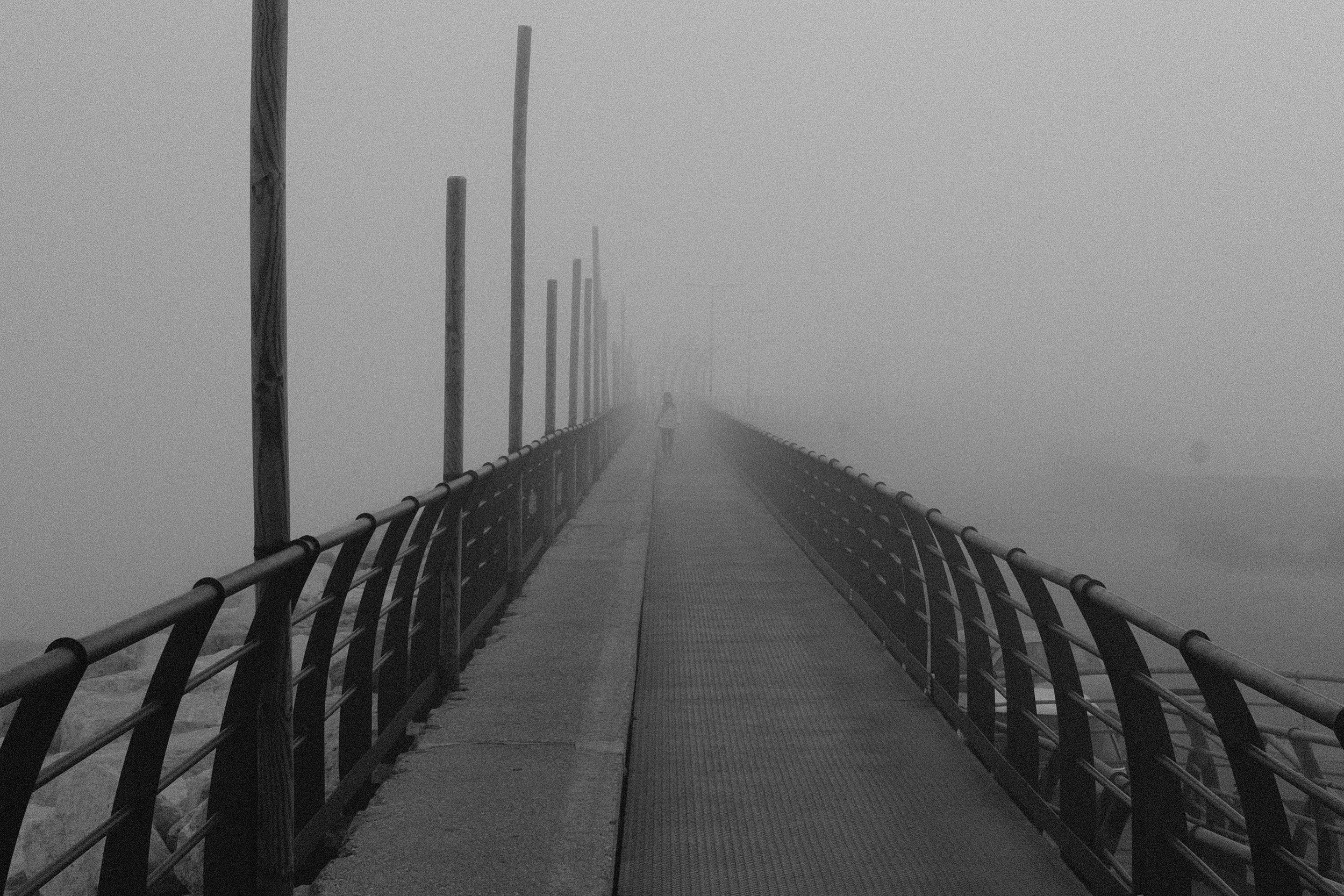 Ponte di ferro avvolto dalla nebbia con una persona in lontananza