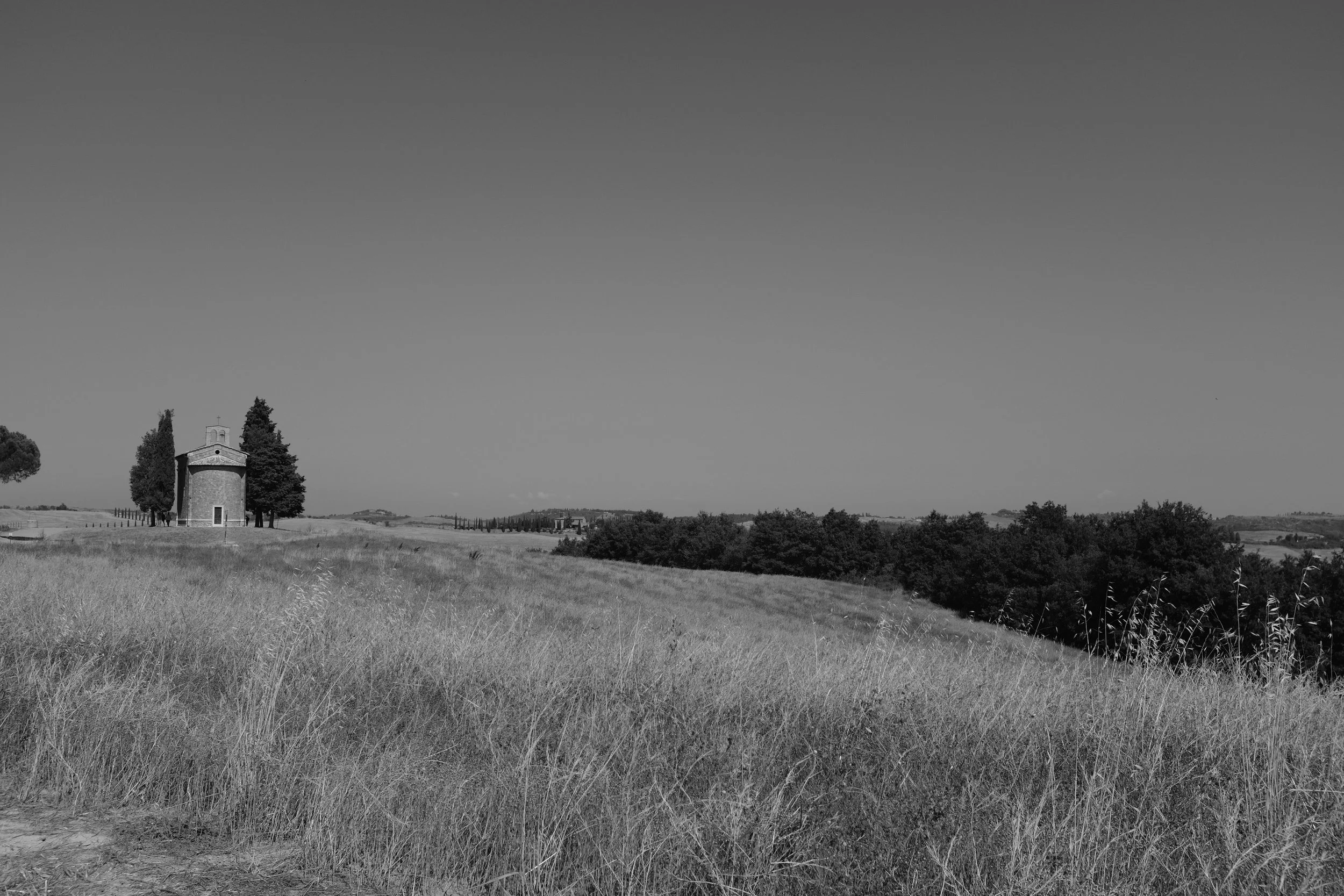 Paesaggio rurale con campo di erba e una piccola chiesa in lontananza
