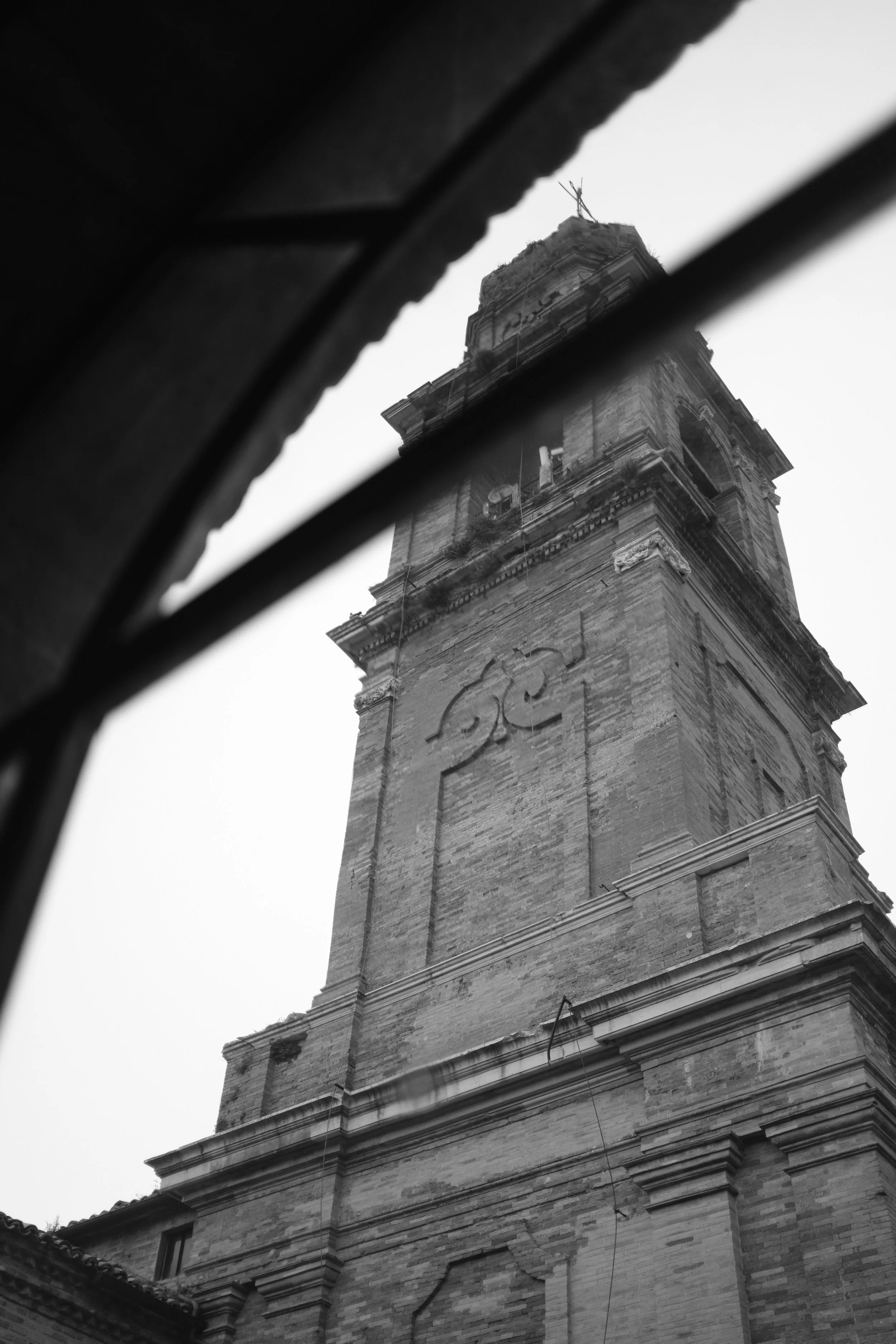 Vista di un campanile in pietra osservato dall'alto, in bianco e nero.