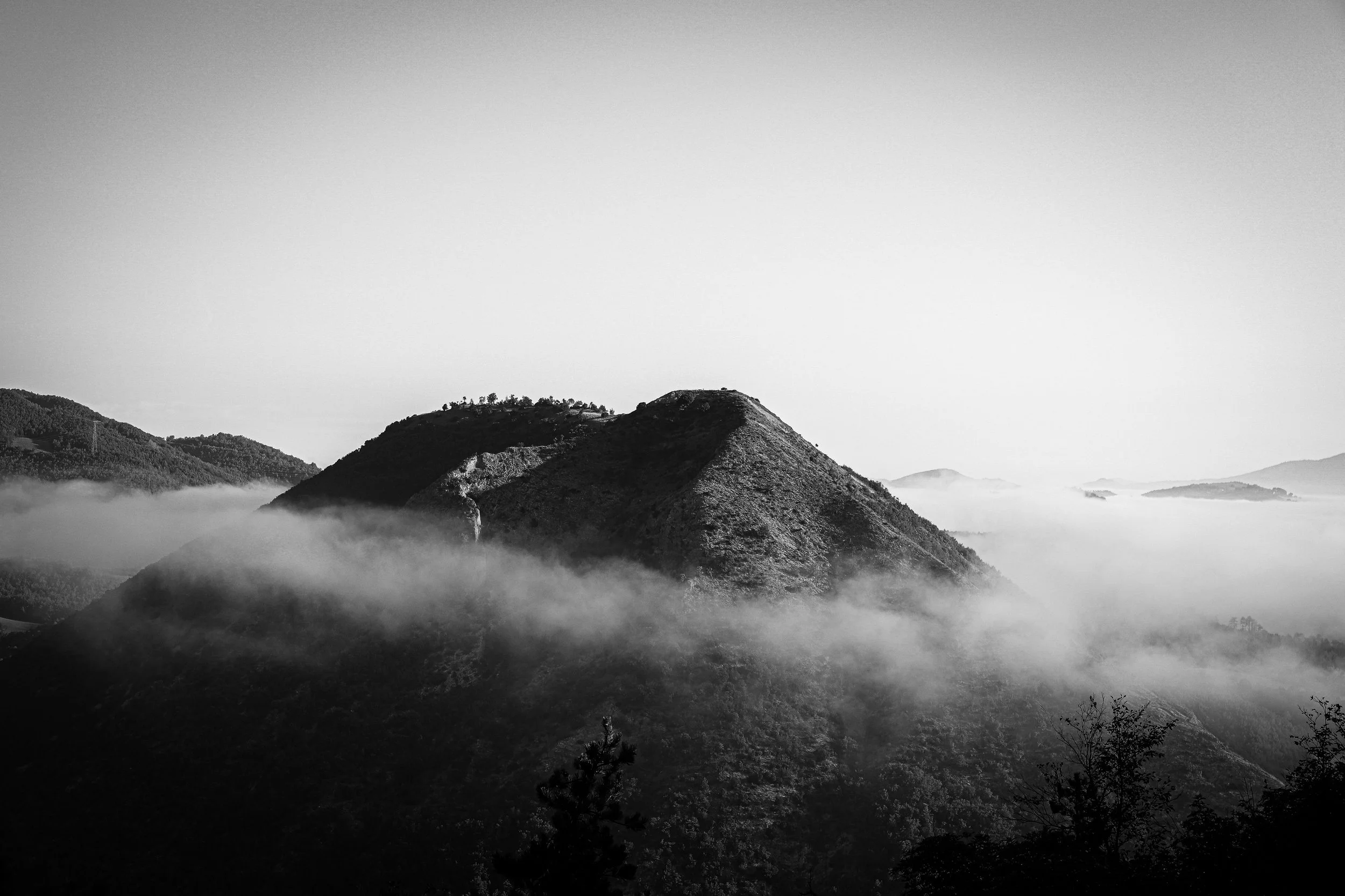 Paesaggio montano nero e bianco con nebbia tra le montagne e cielo chiaro