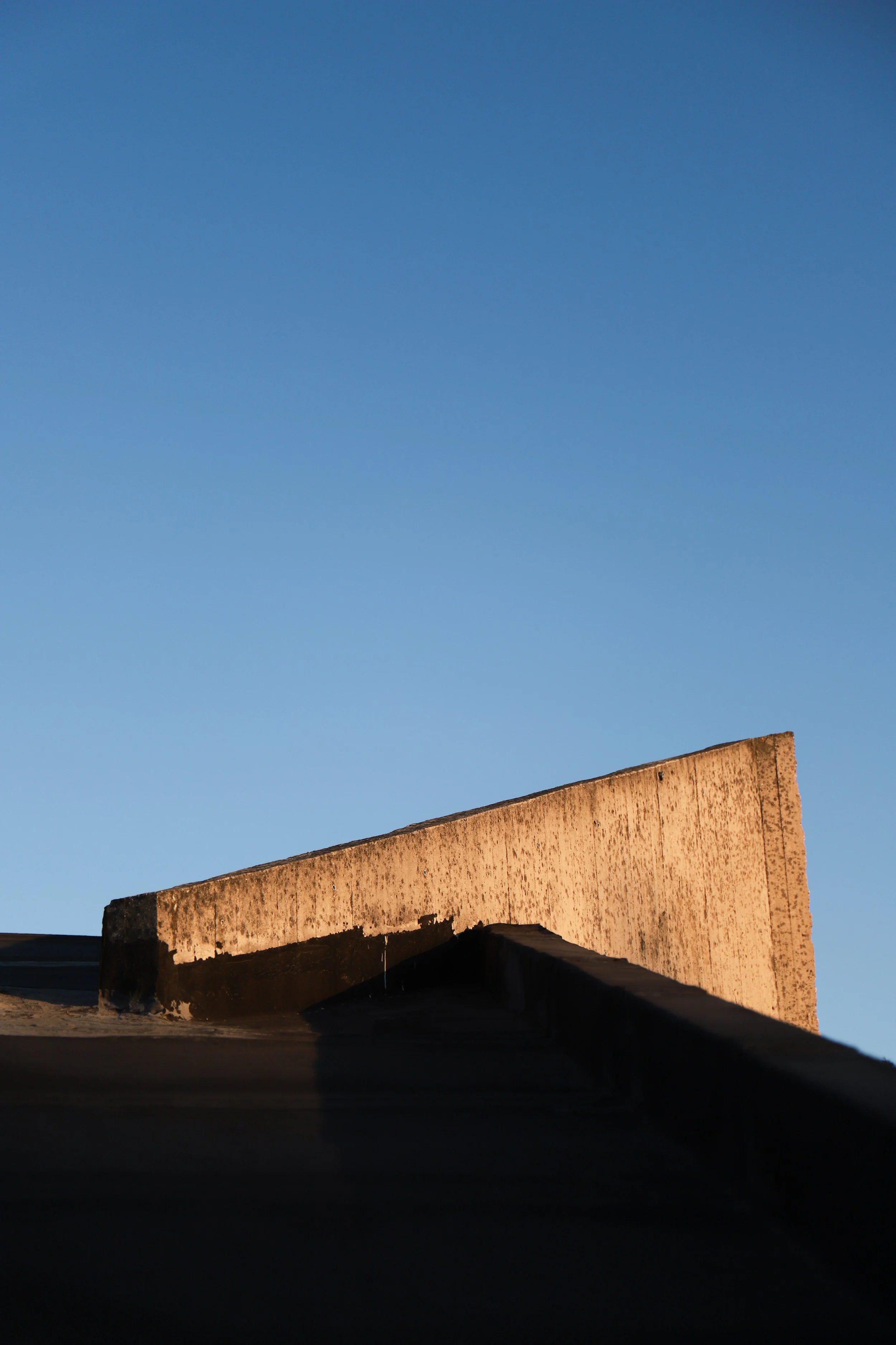 Parete di cemento in ombra con cielo blu chiaro.