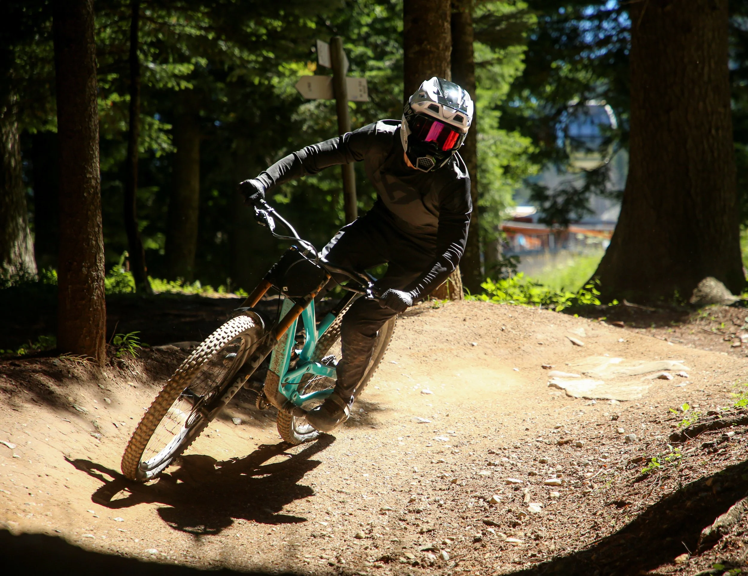 Una persona che fa mountain bike su un sentiero nel bosco, indossando casco e abbigliamento sportivo
