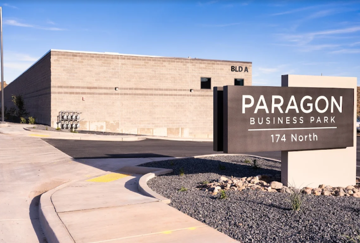 Sign for Paragon Business Park at 174 North in front of a beige commercial building with a blue sky background.