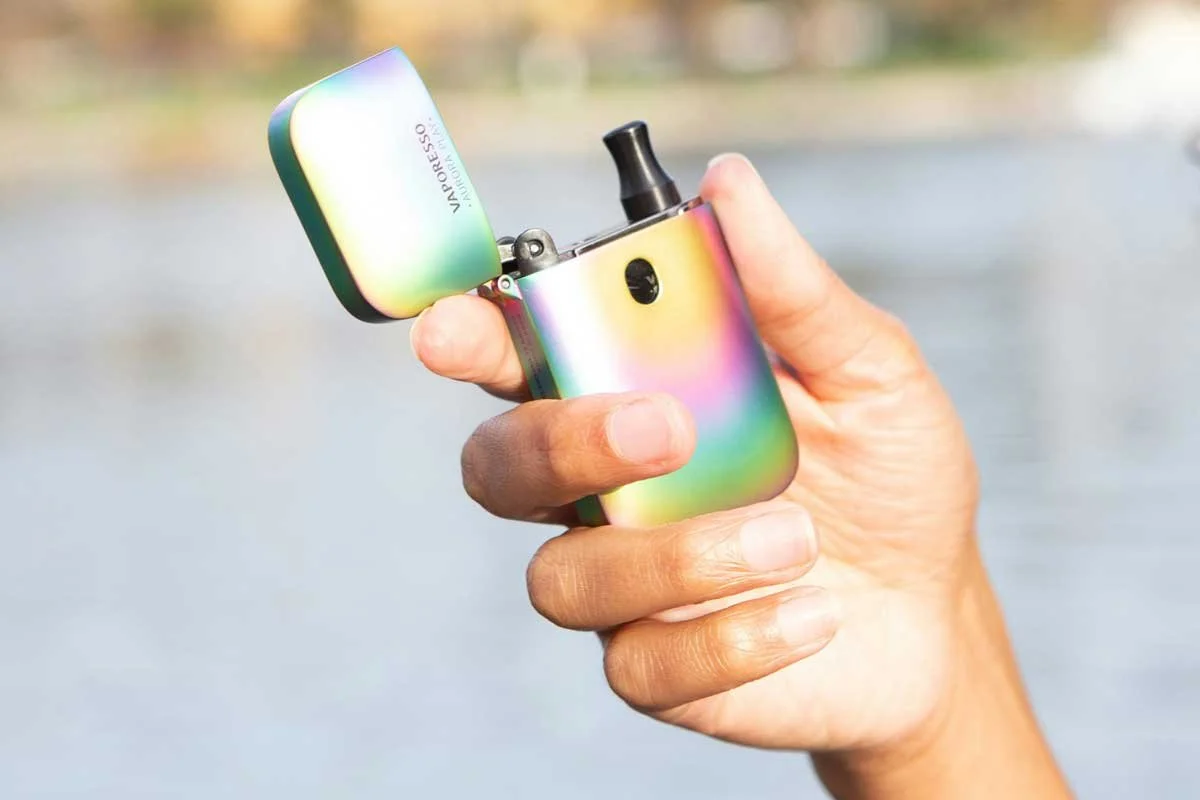 A hand holding a rainbow iridescent portable cannabis vaporizer near the water — shop vapes and vaporizers at b\well, Provincetown's queer owned cannabis dispensary on Cape Cod