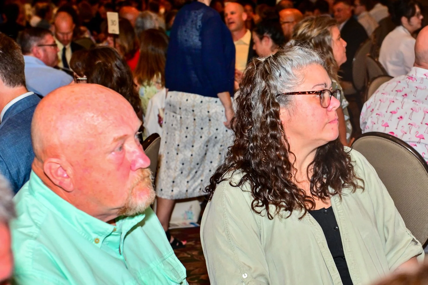 Crowd of people attending a conference or seminar, seated and listening attentively.