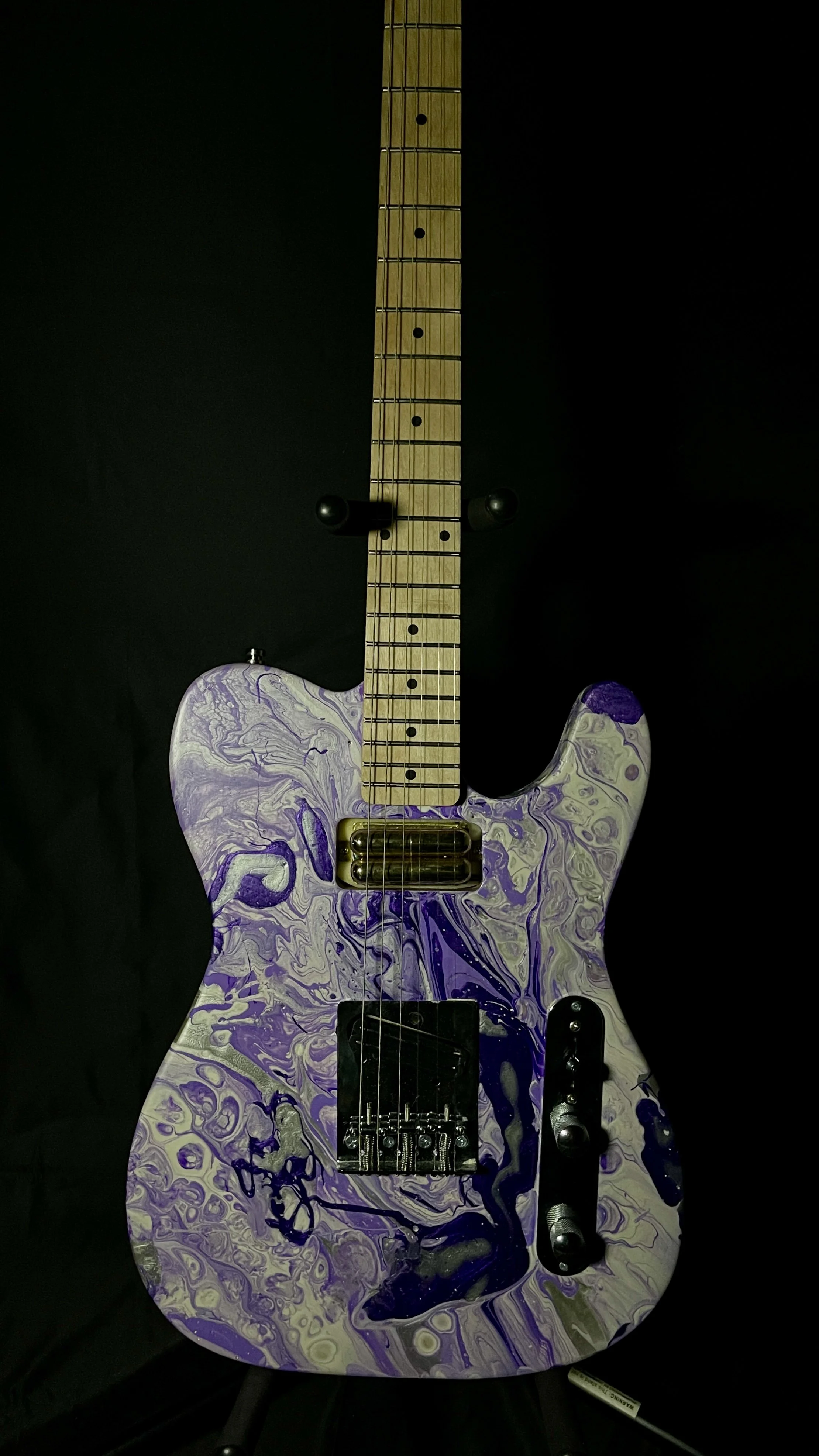 An acrylic poured electric guitar in a wide array of purples and whites. Named Ankhesenamun by Grainrot Guitars.