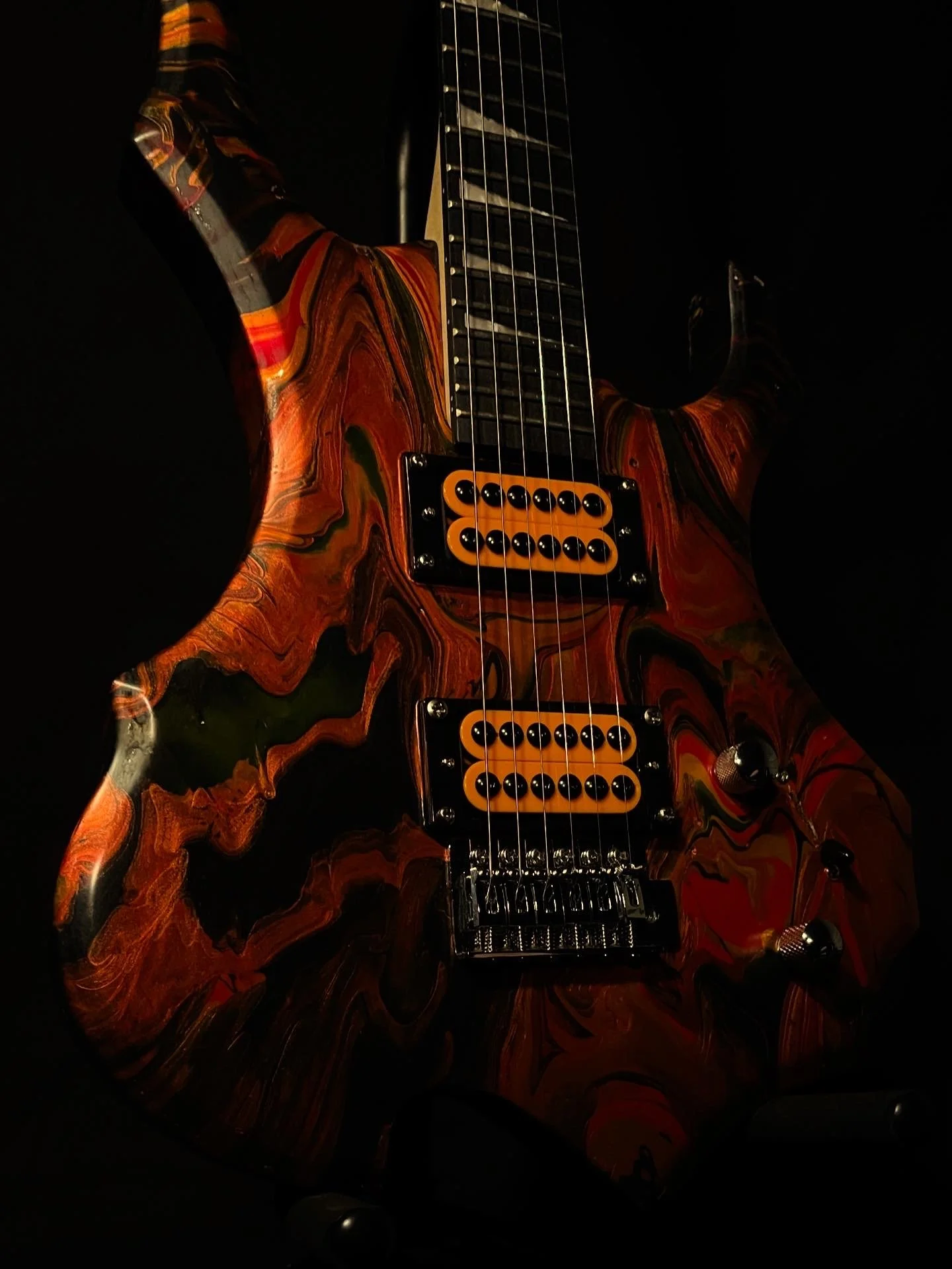A red, black and orange acrylic poured electric guitar named Bhaal by Grainrot Guitars