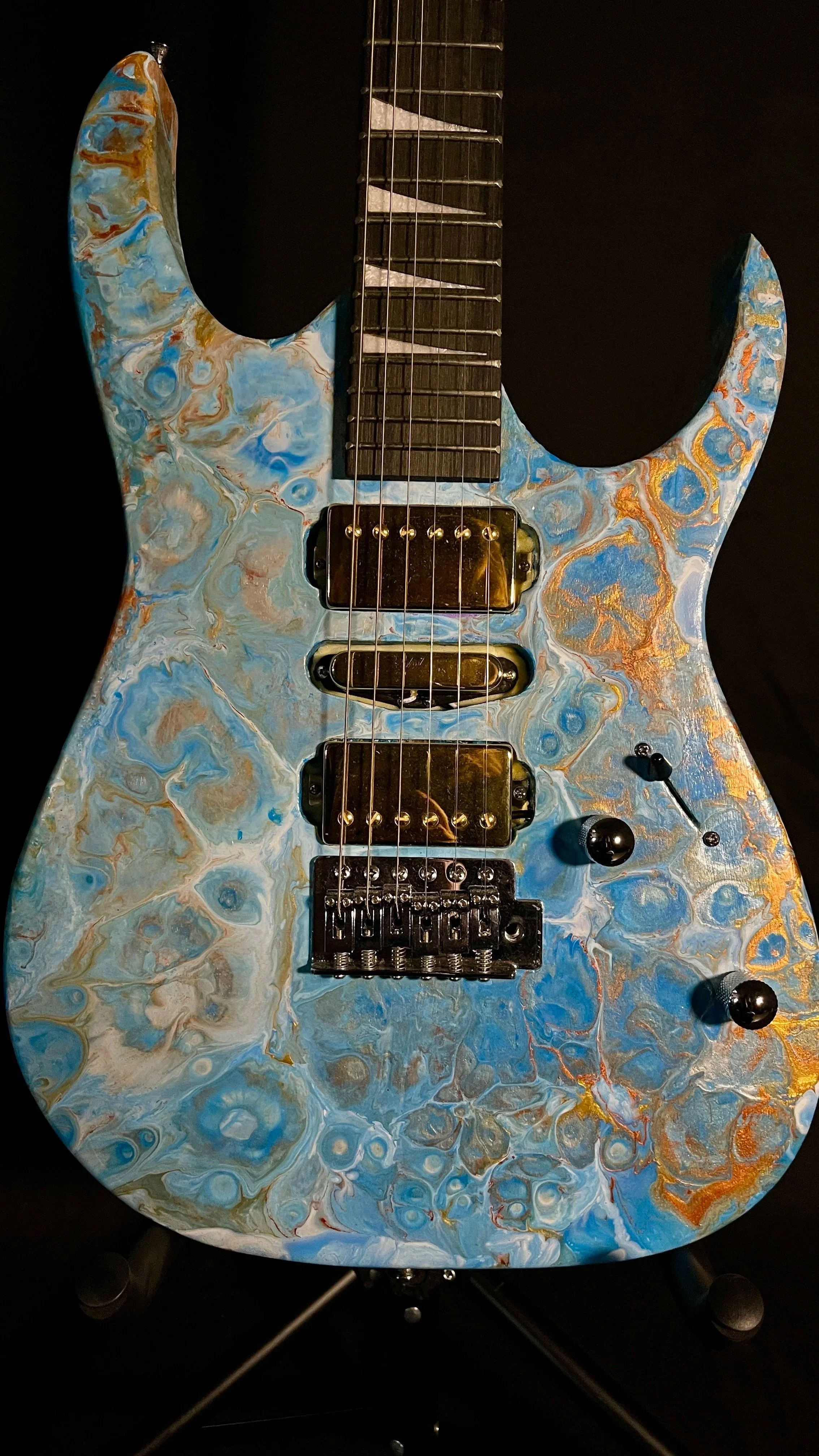 A blue, white and gold acrylic poured electric guitar named Tethys by Grainrot Guitars