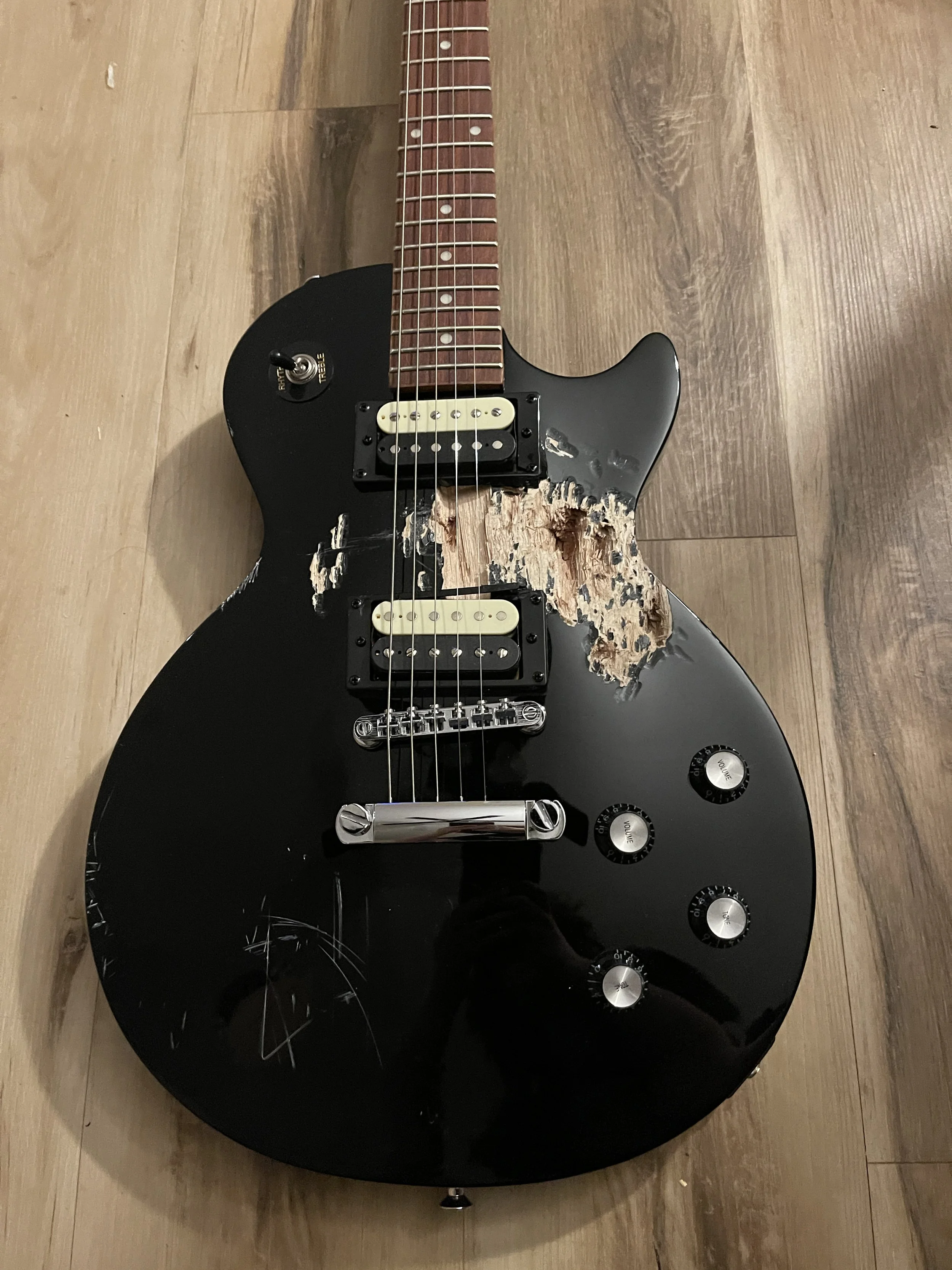 A guitar with a large chunk of it's wooden body taken out of it, before resurrection