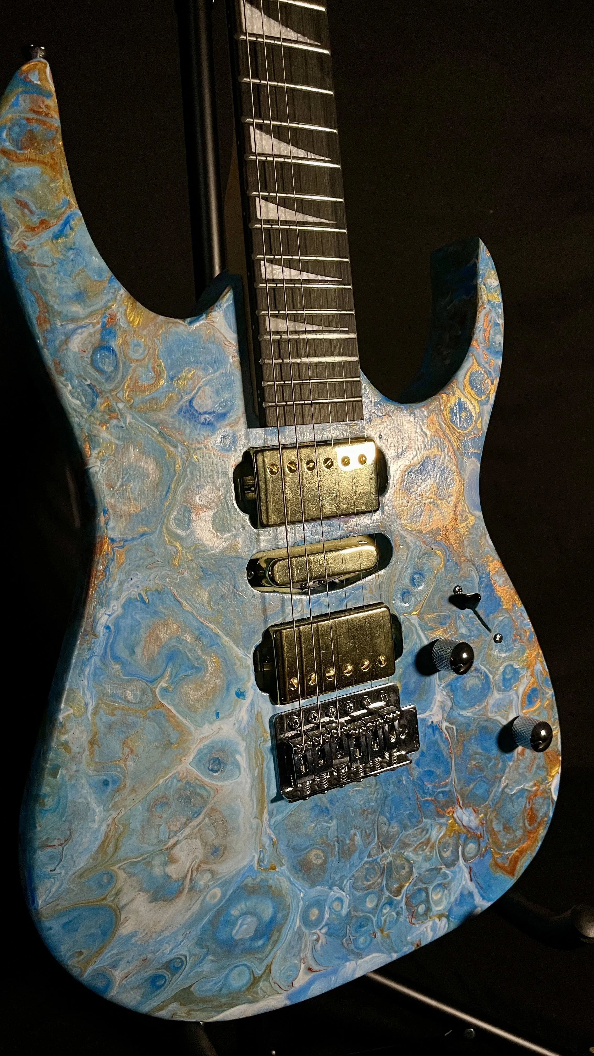 A blue, white and gold acrylic poured electric guitar named Tethys by Grainrot Guitars