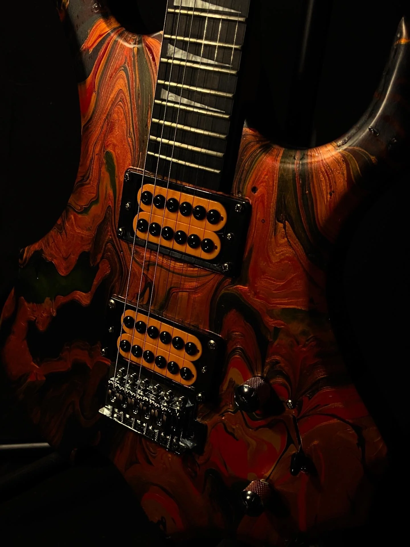 A red, black and orange acrylic poured electric guitar named Bhaal by Grainrot Guitars