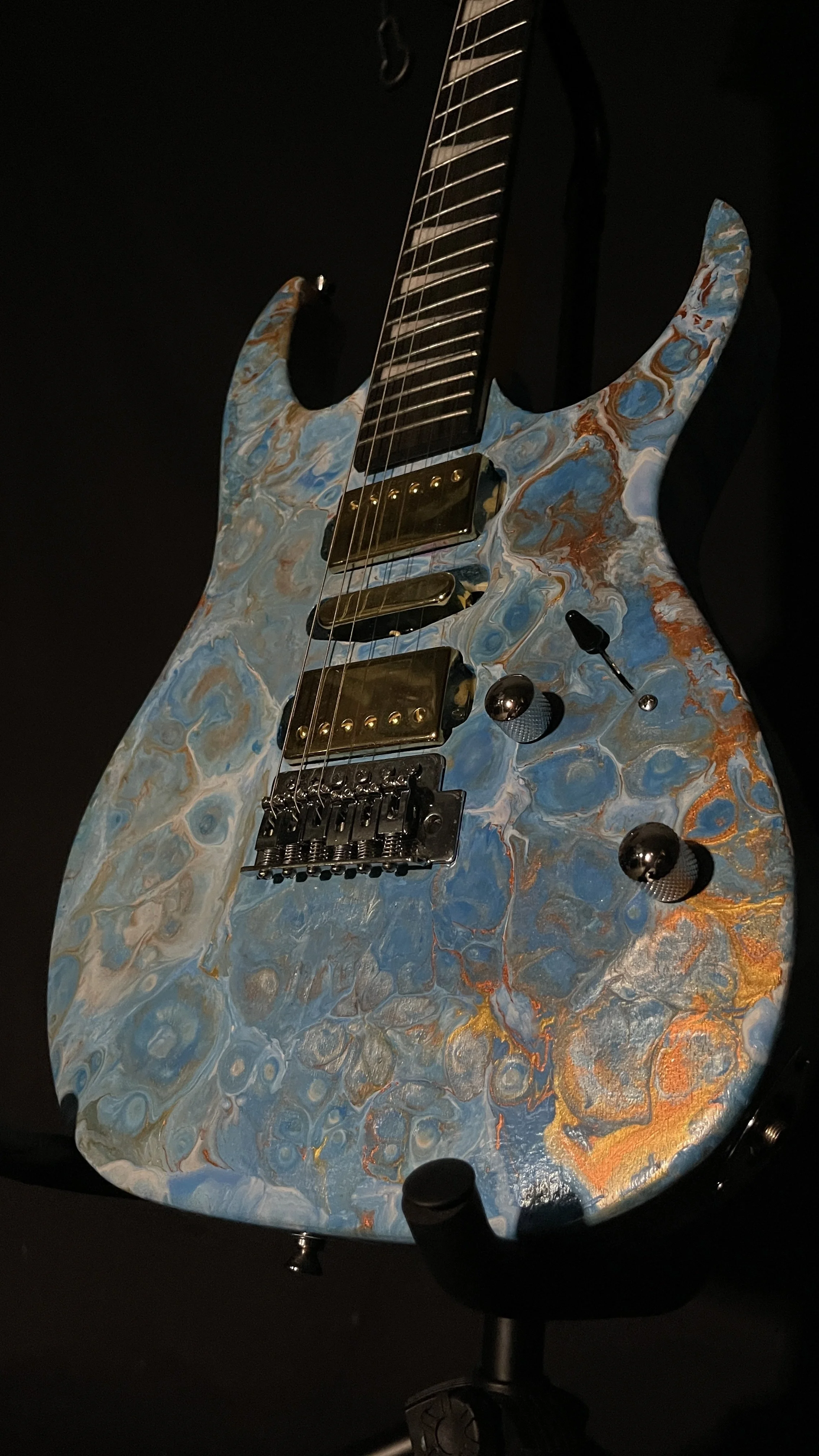 A blue, white and gold acrylic poured electric guitar named Tethys by Grainrot Guitars