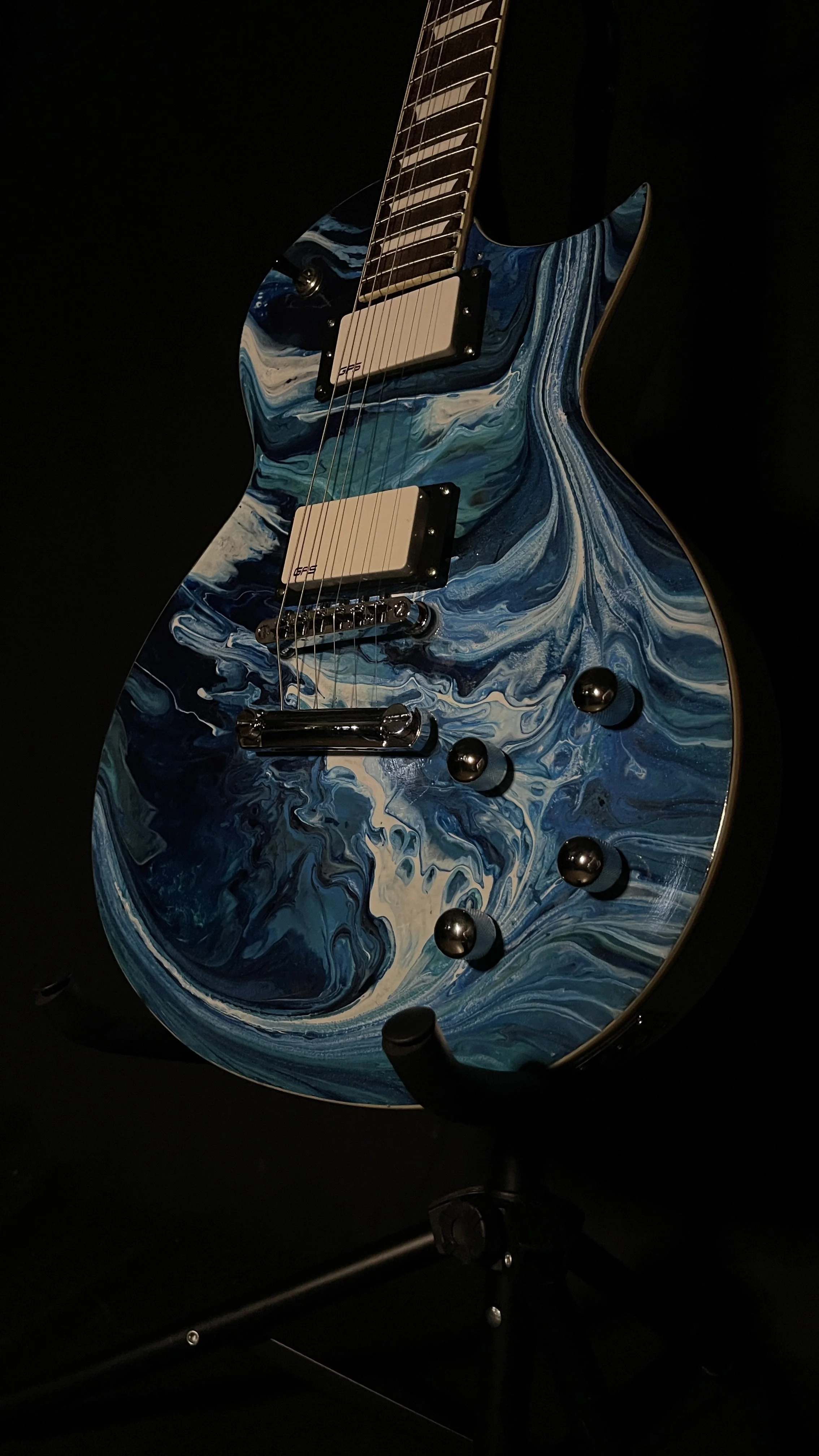 An electric guitar with an acrylic pour in a wide array of blues named orpheus by Grainrot Guitars