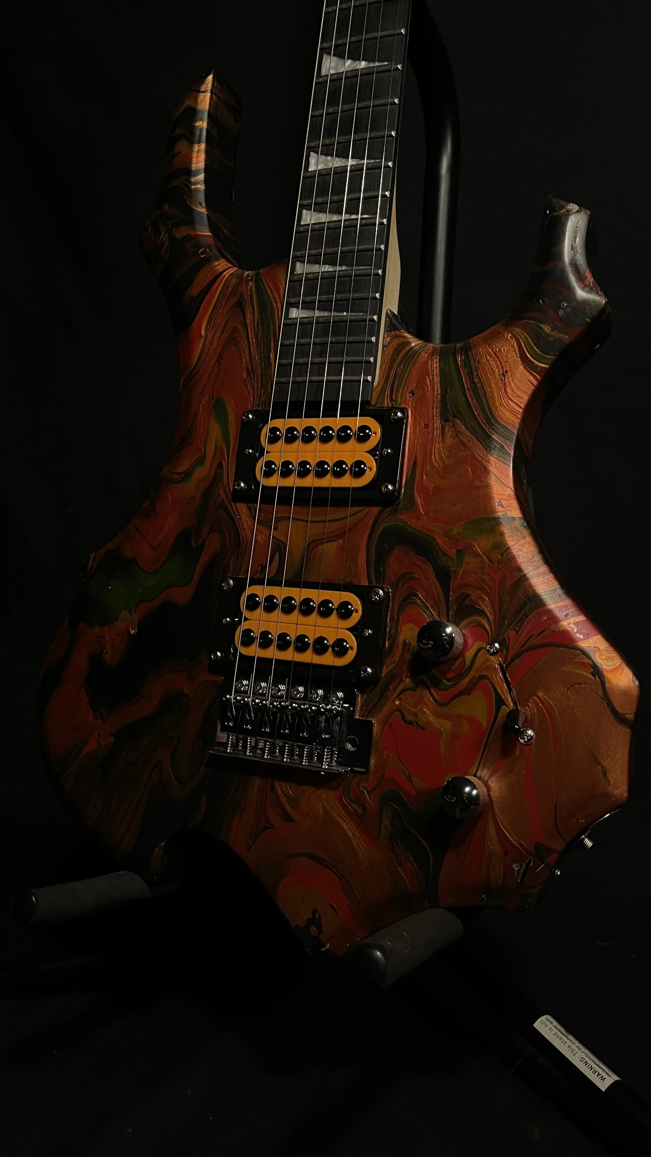 A red, black and orange acrylic poured electric guitar named Bhaal by Grainrot Guitars