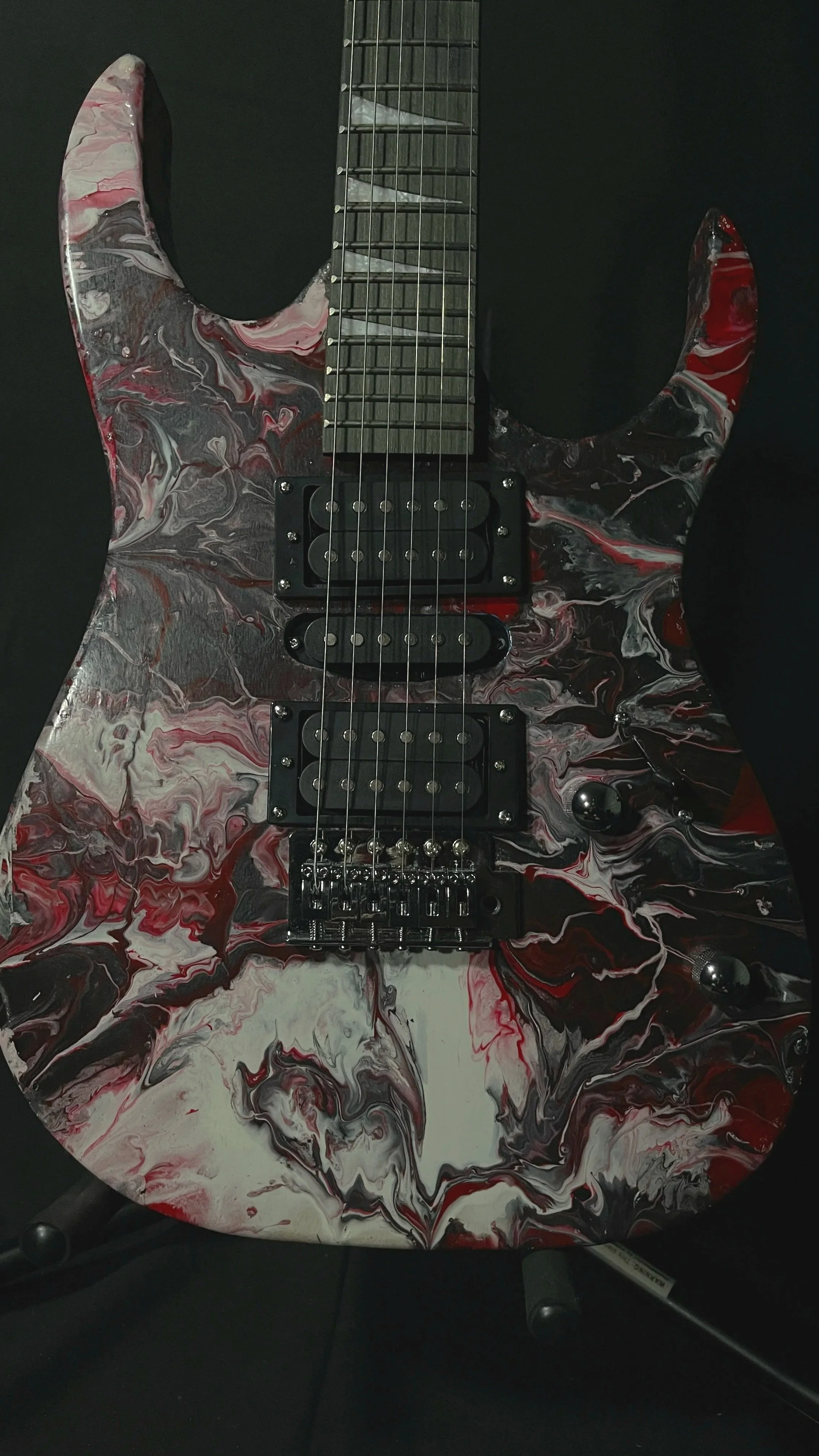 A pink, white and black acrylic poured electric guitar named Luna by Grainrot Guitars