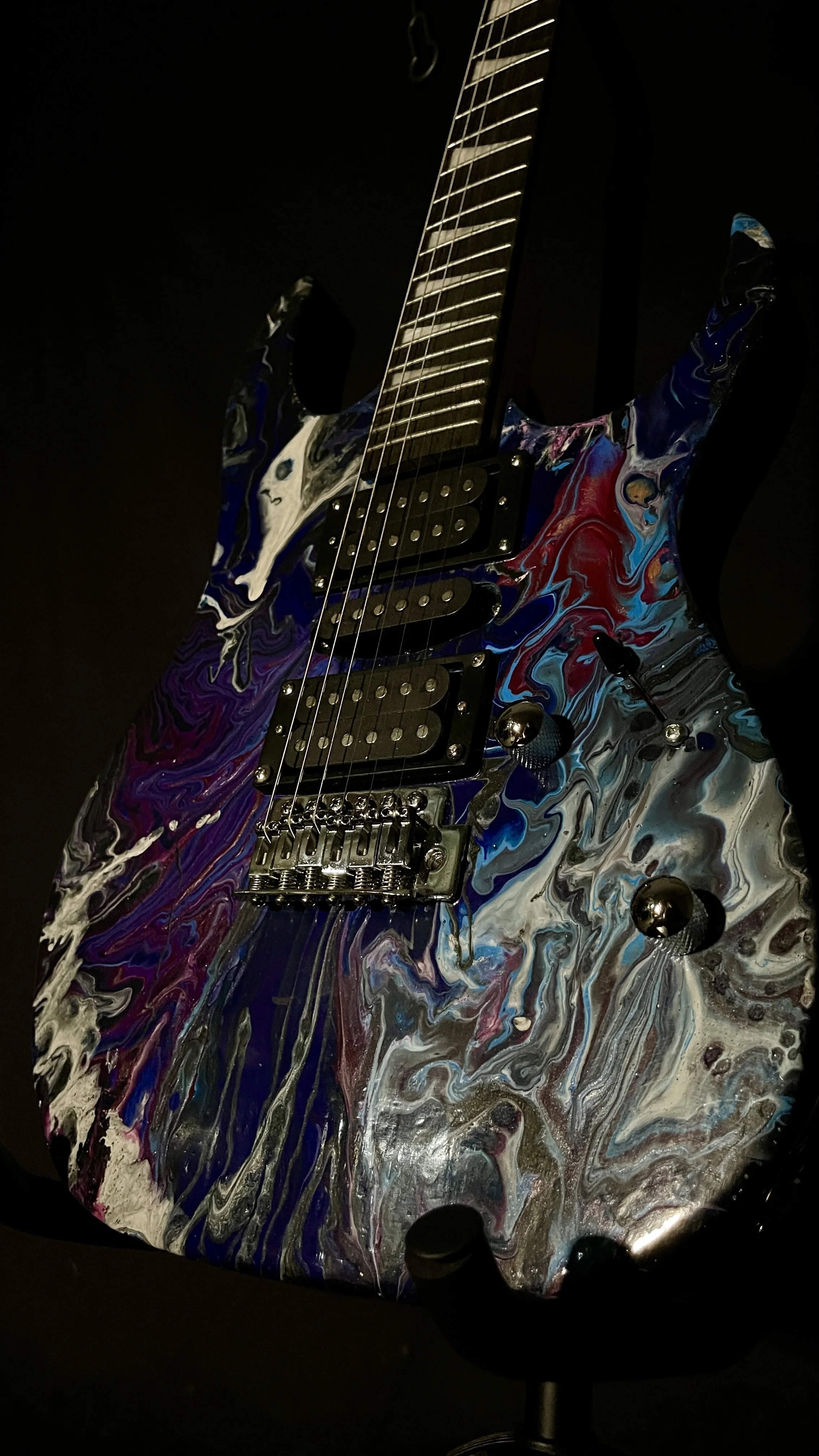 A black, white, blue and purple acrylic poured electric guitar named Nyx by Grainrot Guitars