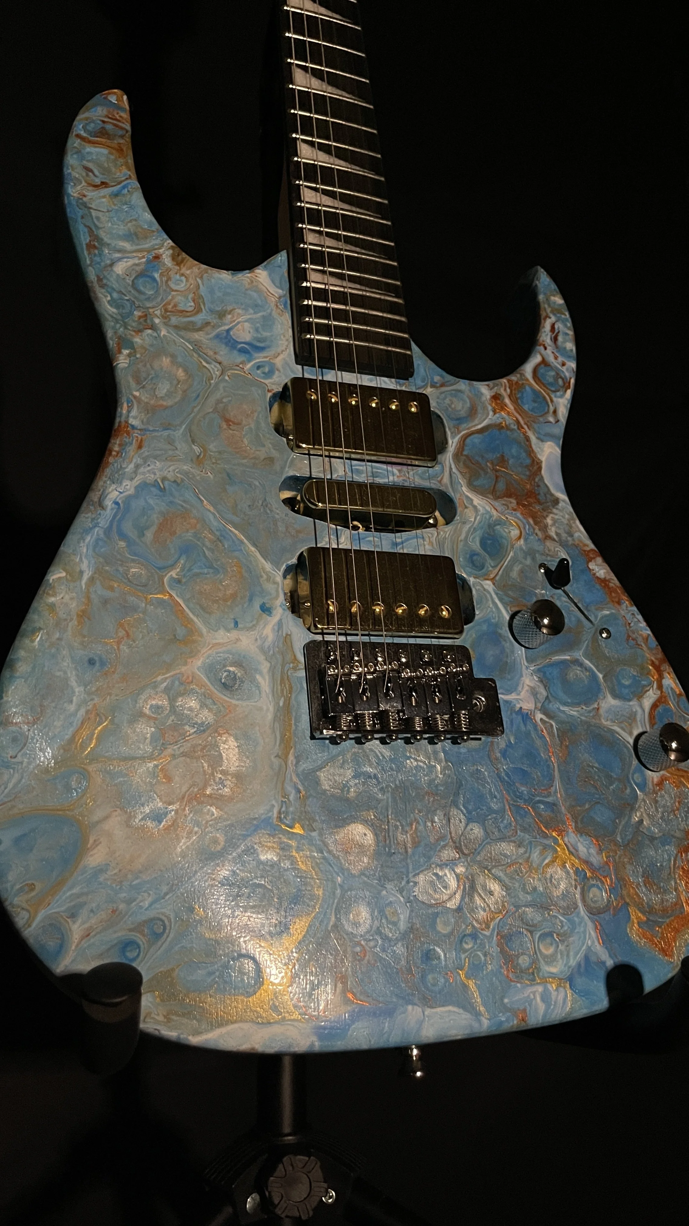 A blue, white and gold acrylic poured electric guitar named Tethys by Grainrot Guitars
