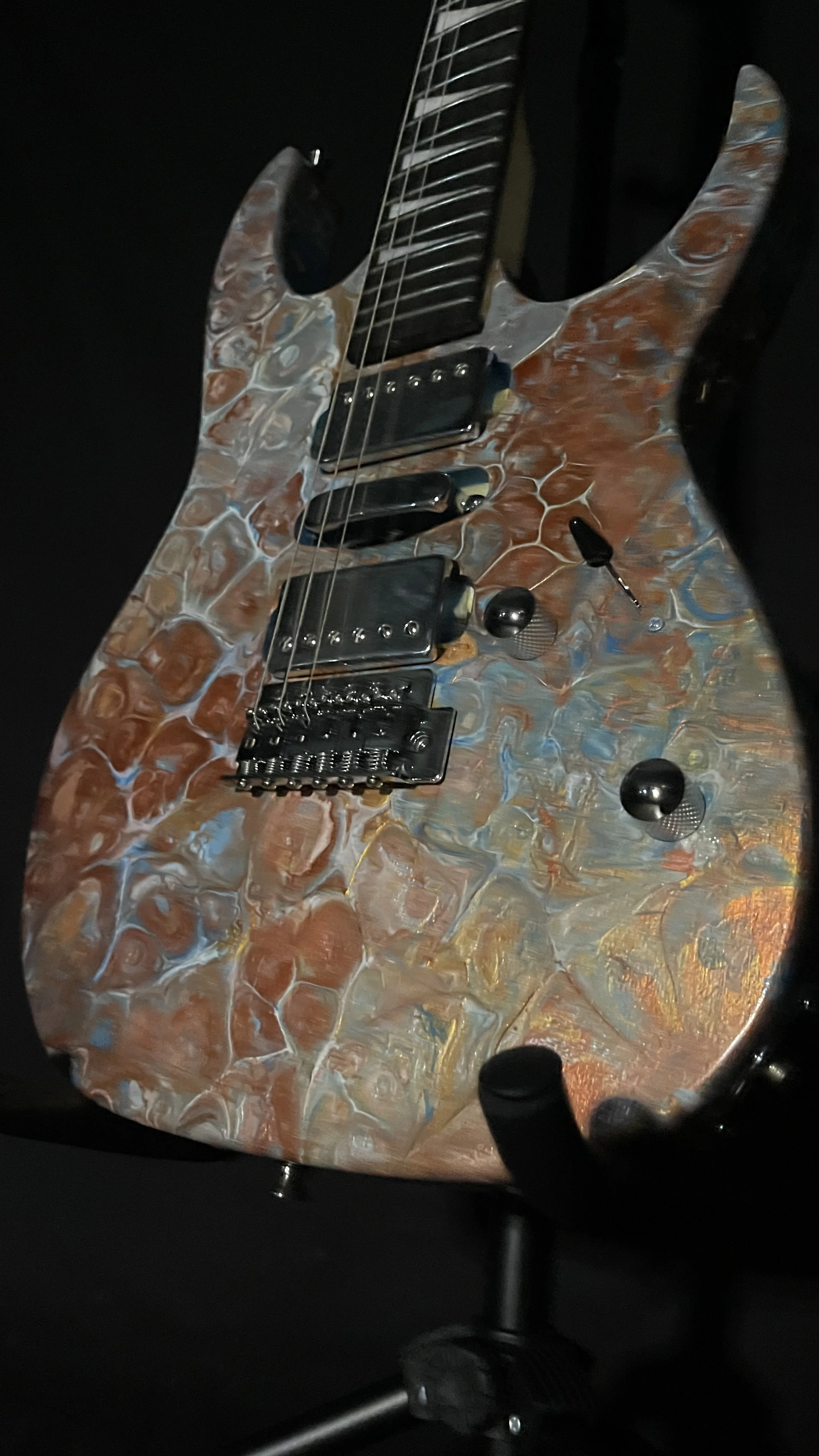 A bronze, gold, silver and blue acrylic poured electric guitar named Tutankhamen by Grainrot Guitars