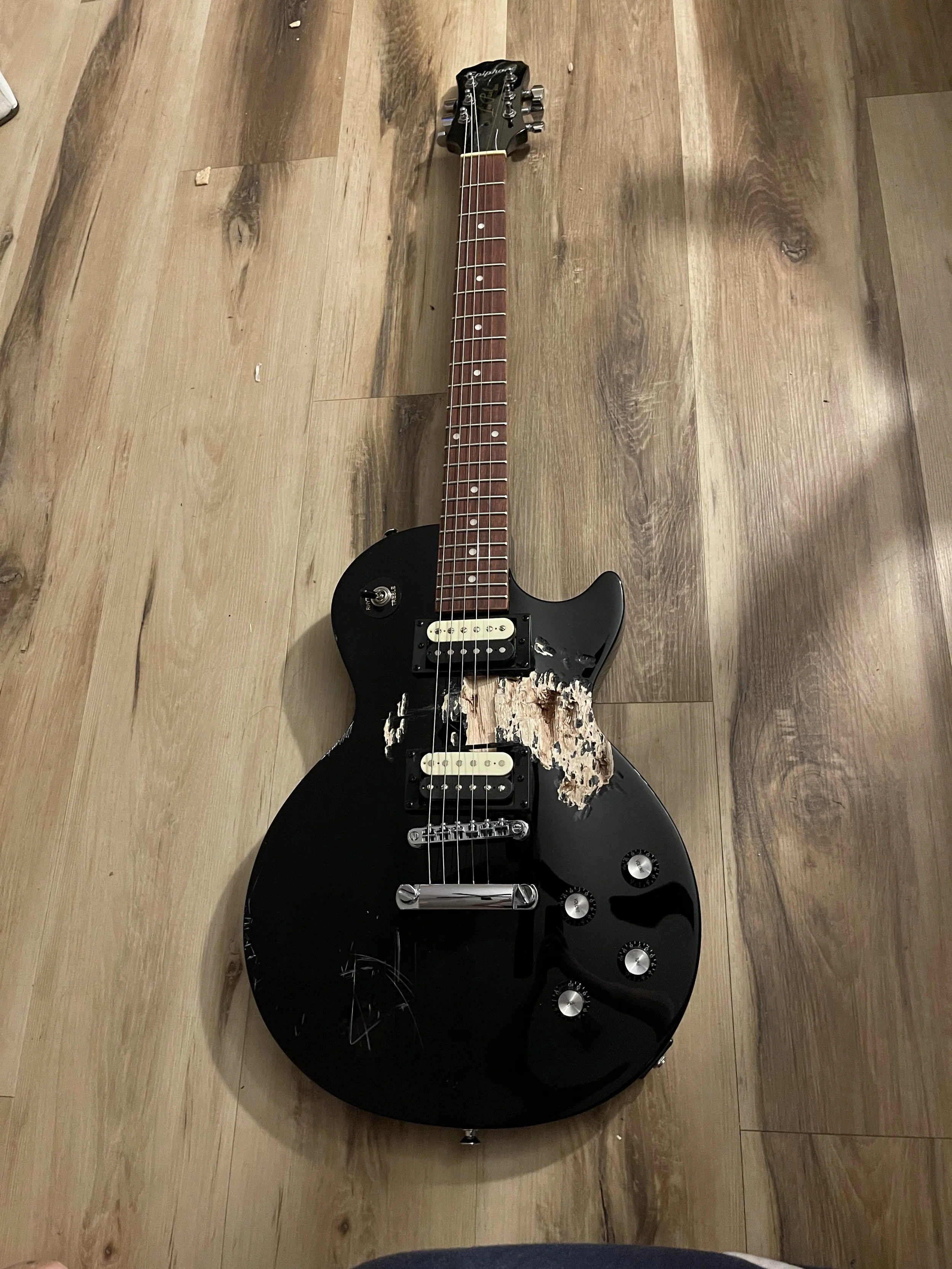 A guitar with a large chunk of it's wooden body taken out of it, before resurrection