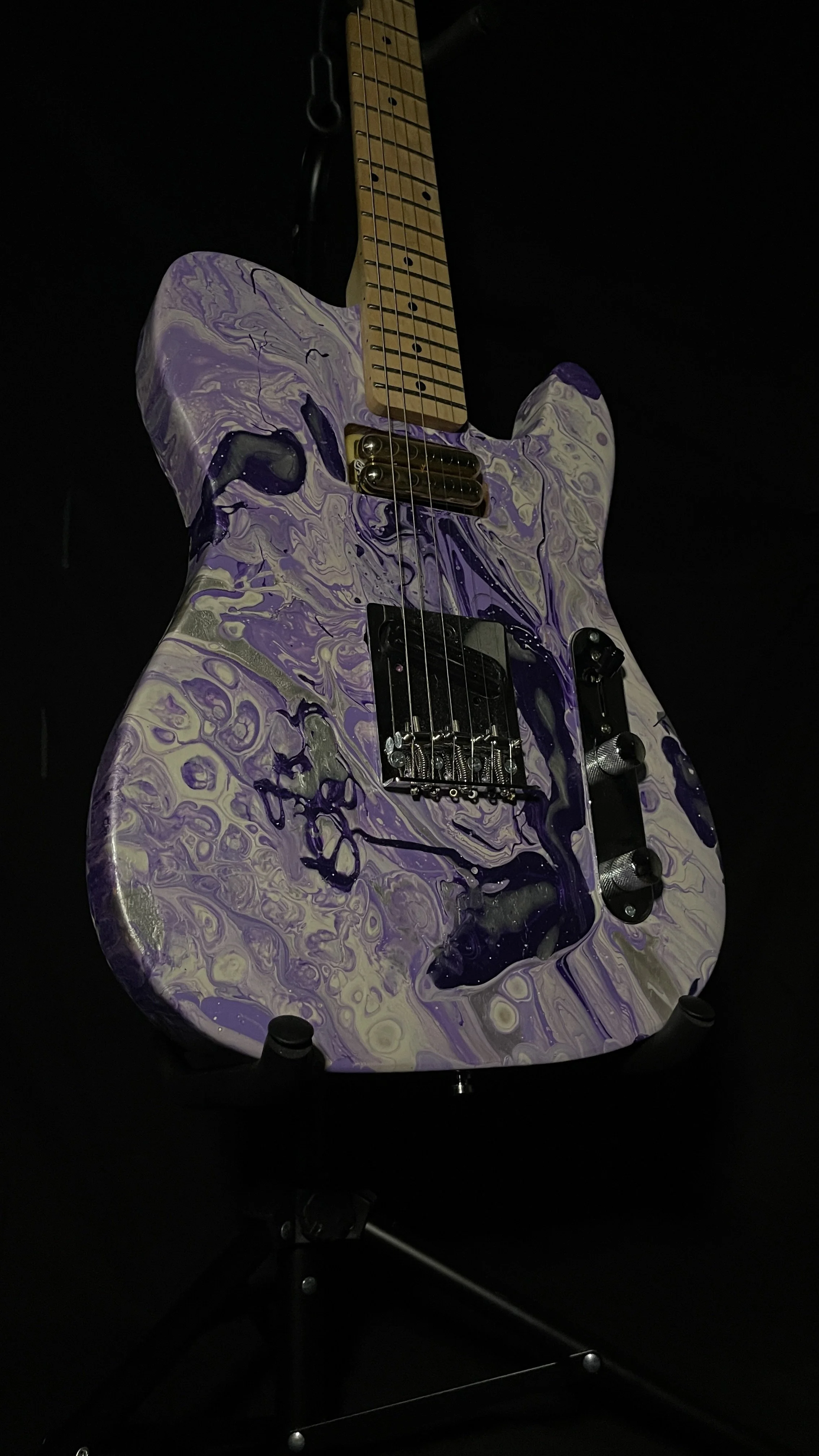 An acrylic poured electric guitar in a wide array of purples and whites. Named Ankhesenamun by Grainrot Guitars.