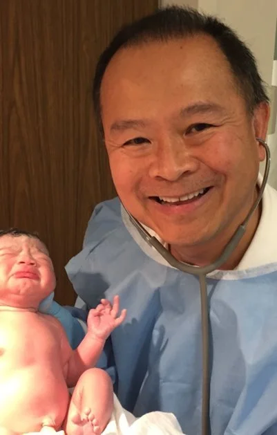 Photo of Dr. Chen holding a newborn
