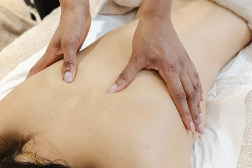 Person receiving a massage on their back from a massage therapist in a spa or massage therapy setting.