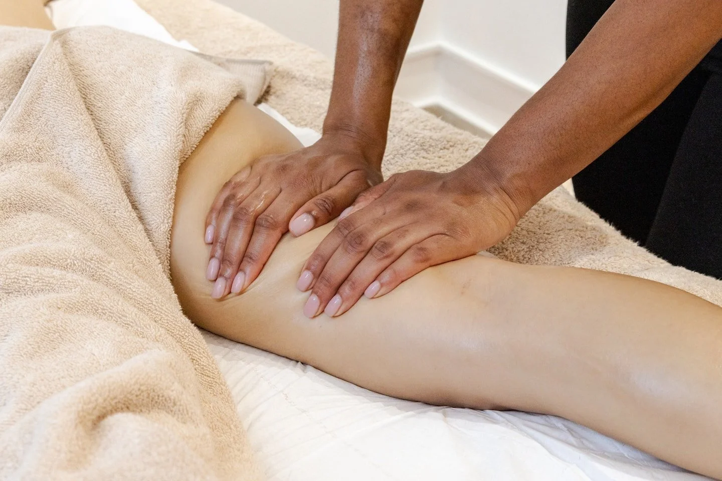 A person receiving a massage on their leg from a therapist in a therapy room.