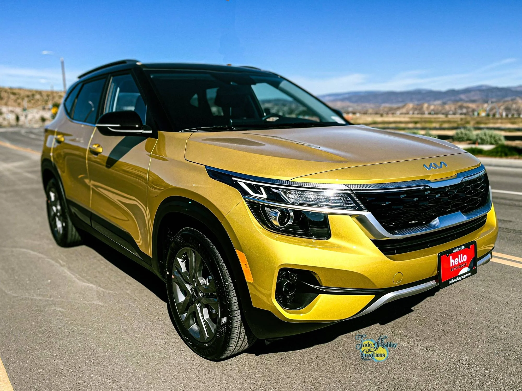 Yellow Kia SUV parked on the side of the road with a scenic background of mountains and blue sky.