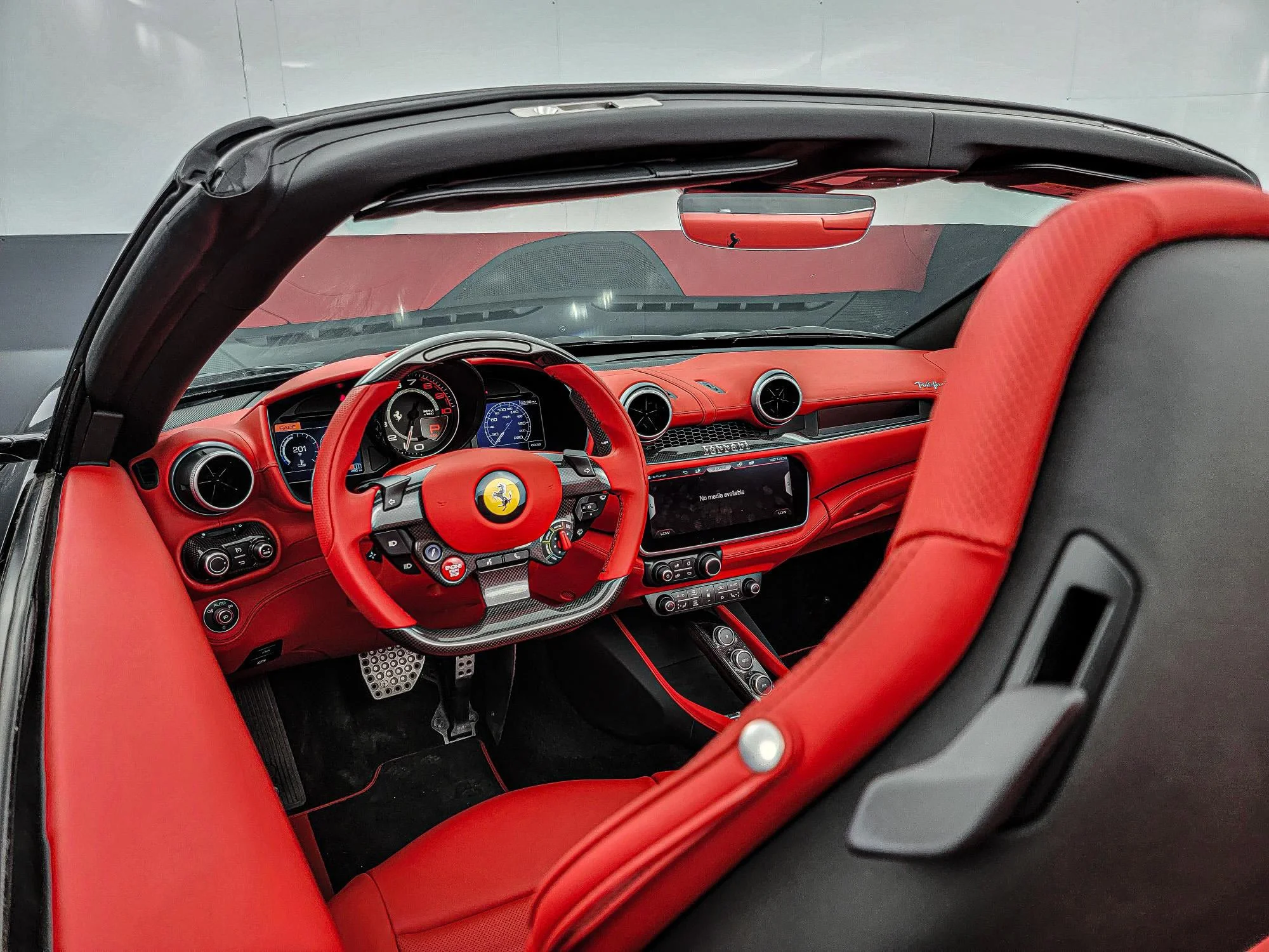 Interior view of a red Ferrari convertible showing the steering wheel, dashboard, and seats.