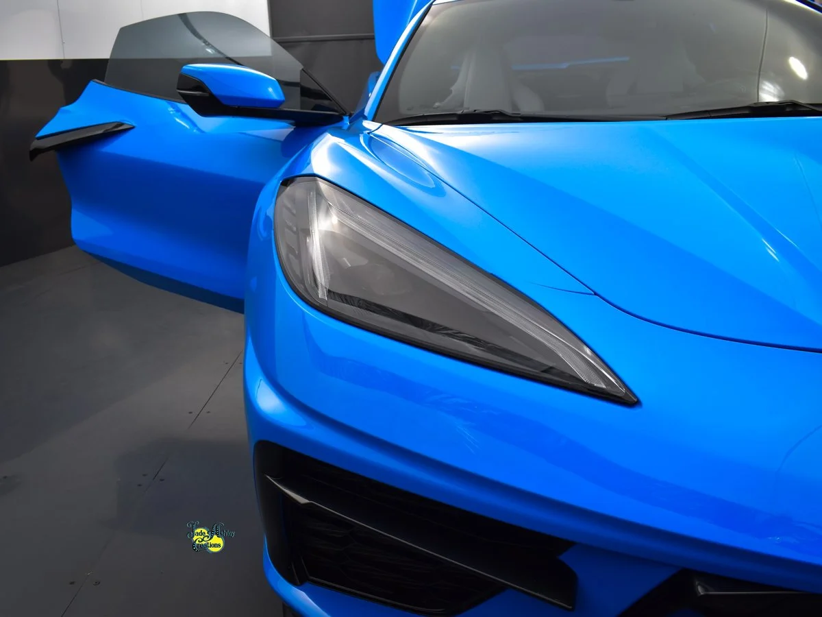 Close-up of the front and side of a bright blue sports car with sleek design, sharp headlights, and aerodynamic features.