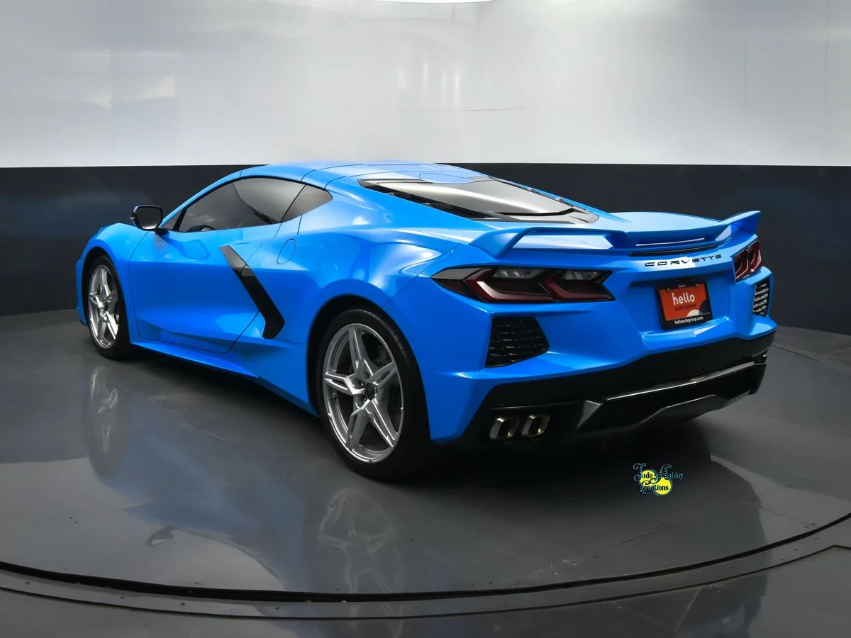 A bright blue Chevrolet Corvette sports car parked indoors on a reflective floor.