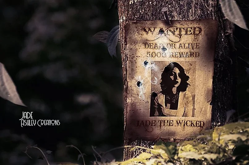 A worn, tattered wanted poster on a tree, offering a $5,000 reward for Jade the Wicked, featuring a silhouette of a woman's face with flowing hair. The poster is old, crumpled, and has spider webs and holes.