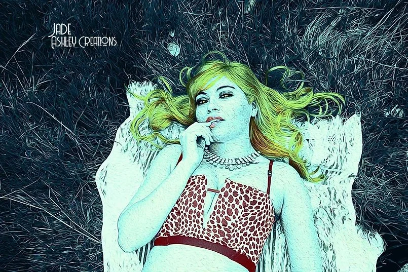 A woman with greenish hair lying on a textured surface, wearing a leopard print top and a pearl necklace, with her hand near her face.