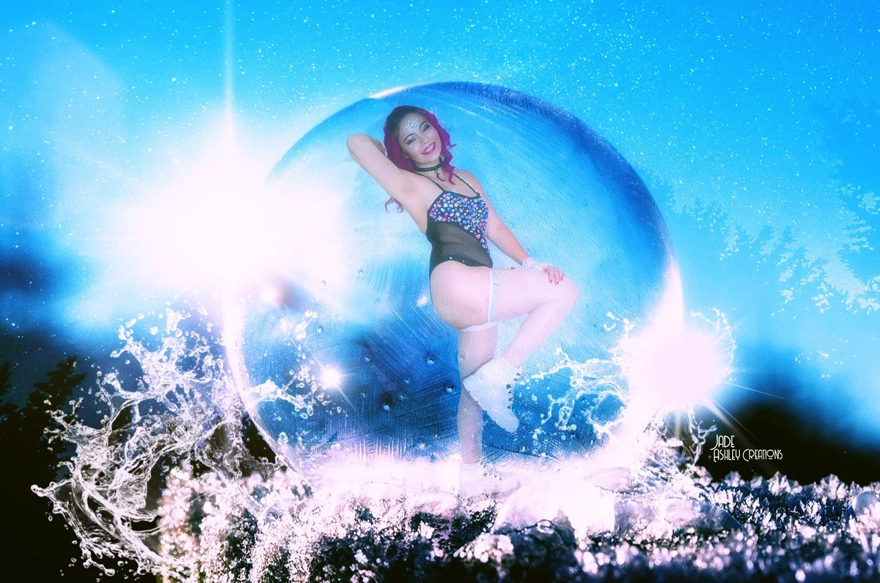 A woman with purple hair wearing a black and multicolored top and white thigh-high stockings poses inside a giant ice sphere, surrounded by splashing water and bright light effects.