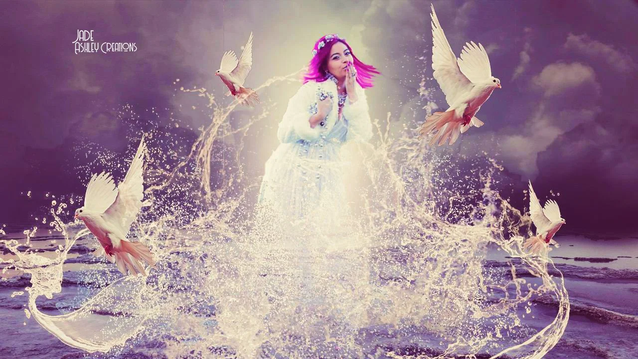 A woman with pink hair and a white dress standing in the water surrounded by five white doves flying and splashing water.