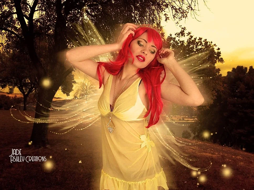 A woman with long red hair and a yellow dress standing outdoors at sunset with glowing light effects and sparkles around her.