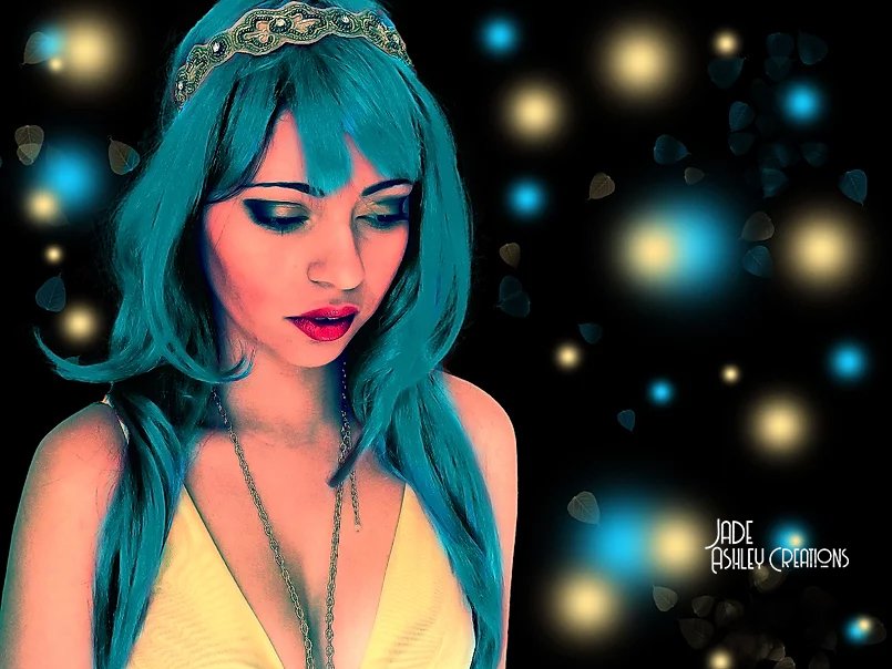 A woman with vibrant blue hair wearing a beaded headband and a yellow top, surrounded by glowing bokeh lights.