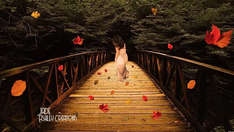 A woman in a white dress walking on a wooden bridge surrounded by falling autumn leaves.
