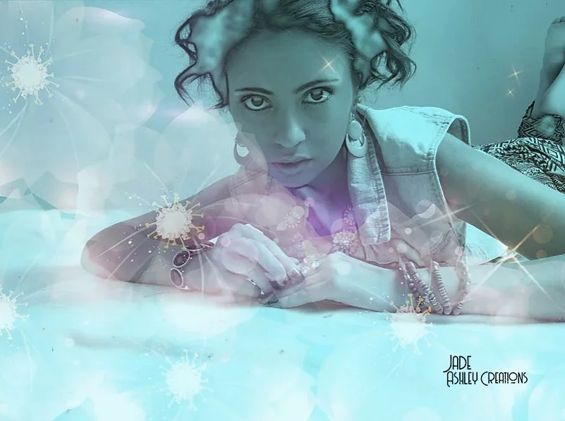 A woman with curly hair lying on her stomach on a surface, looking at the camera. The image has a blue and purple overlay with illustrations of virus particles and light spots, giving a digital or surreal effect.