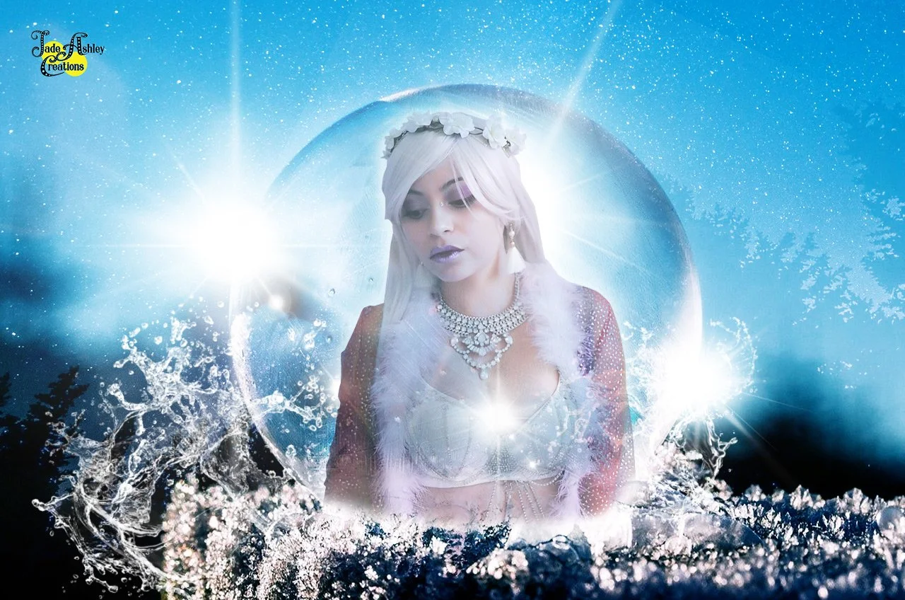 A woman with blonde hair, adorned with a flower crown, wearing jewelry and a white feathered shawl, appears inside a snow globe with water and ice splashing around. The background is a starry sky with bright light sources creating a magical, mystical