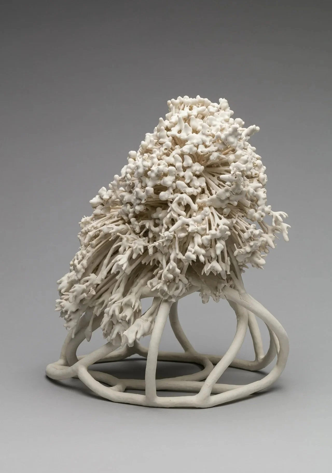 A white porcelain ceramic sculpture resembling coral with intricate branching details and winding base