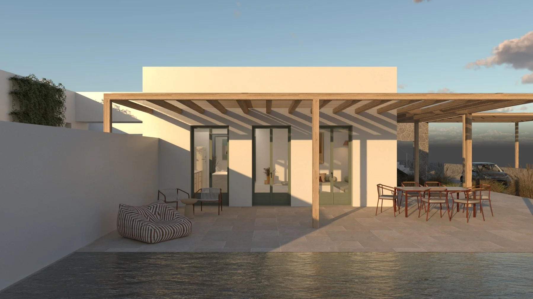 Modern house with a covered patio, outdoor seating, and view of a body of water at sunset.