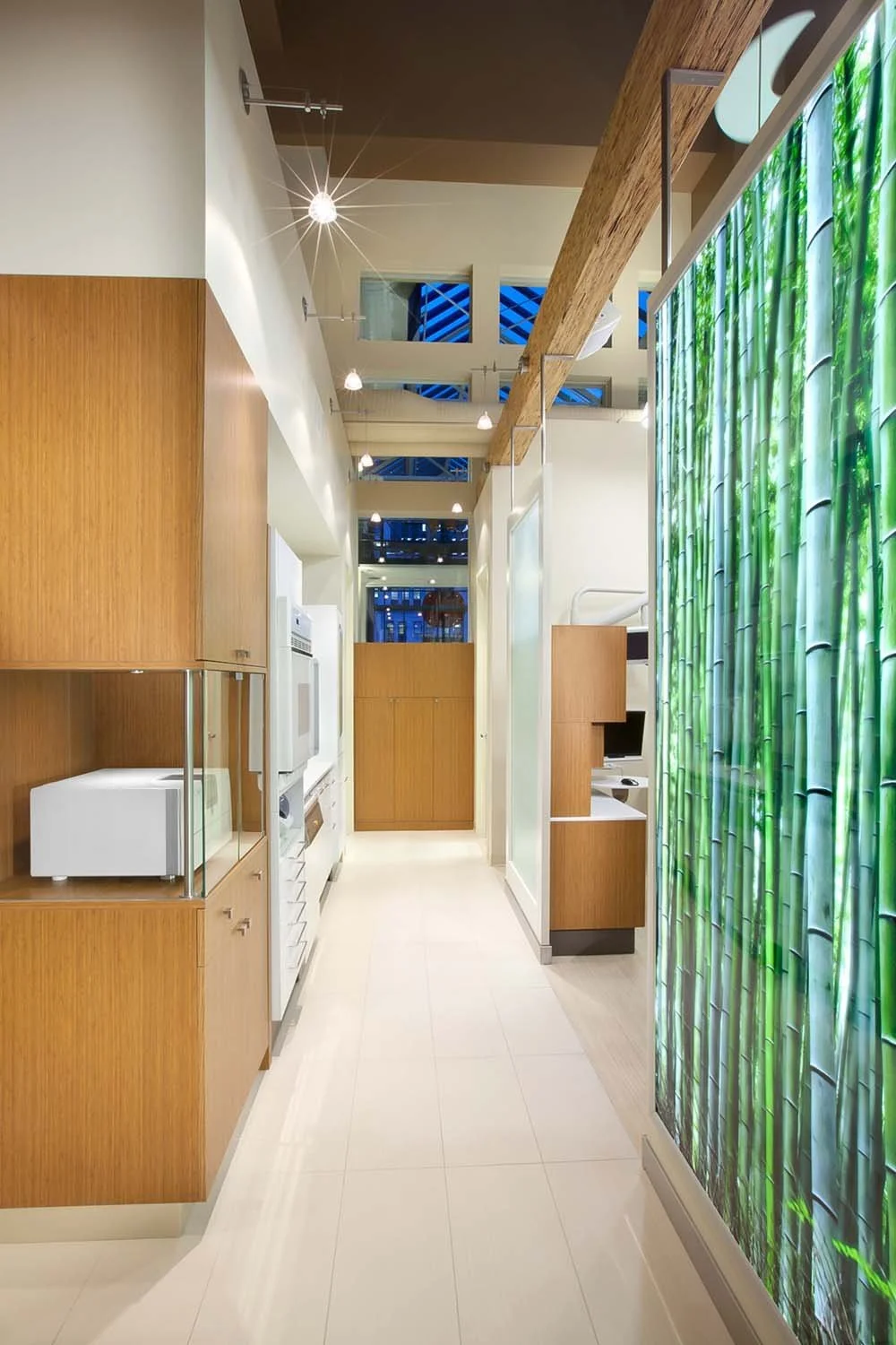 A dental healthcare center hallway with white appliances, wooden cabinets, and a bamboo-themed curtain on the right side.
