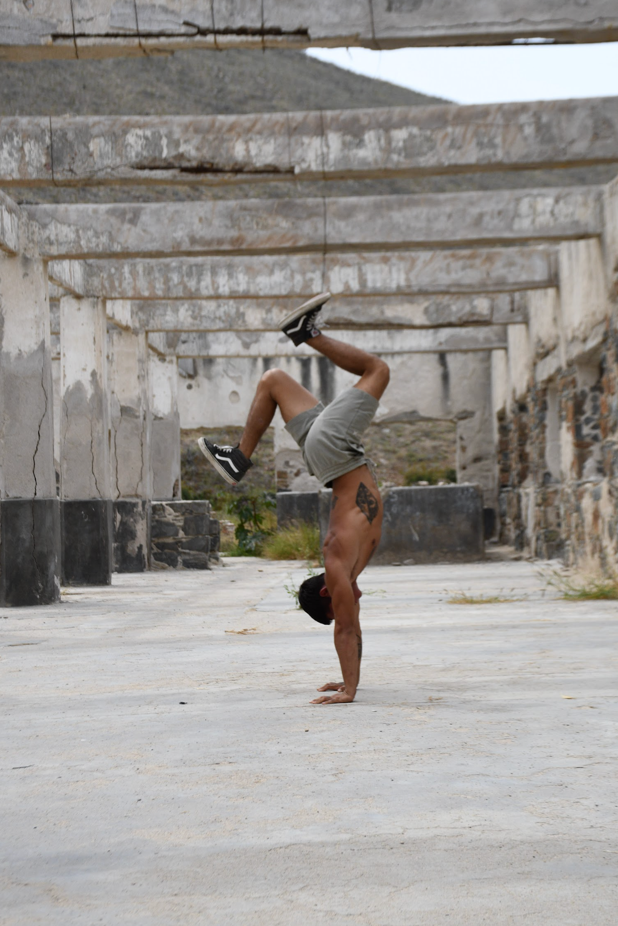 Hombre haciendo una posición de calistenia en un espacio abierto y en ruinas.